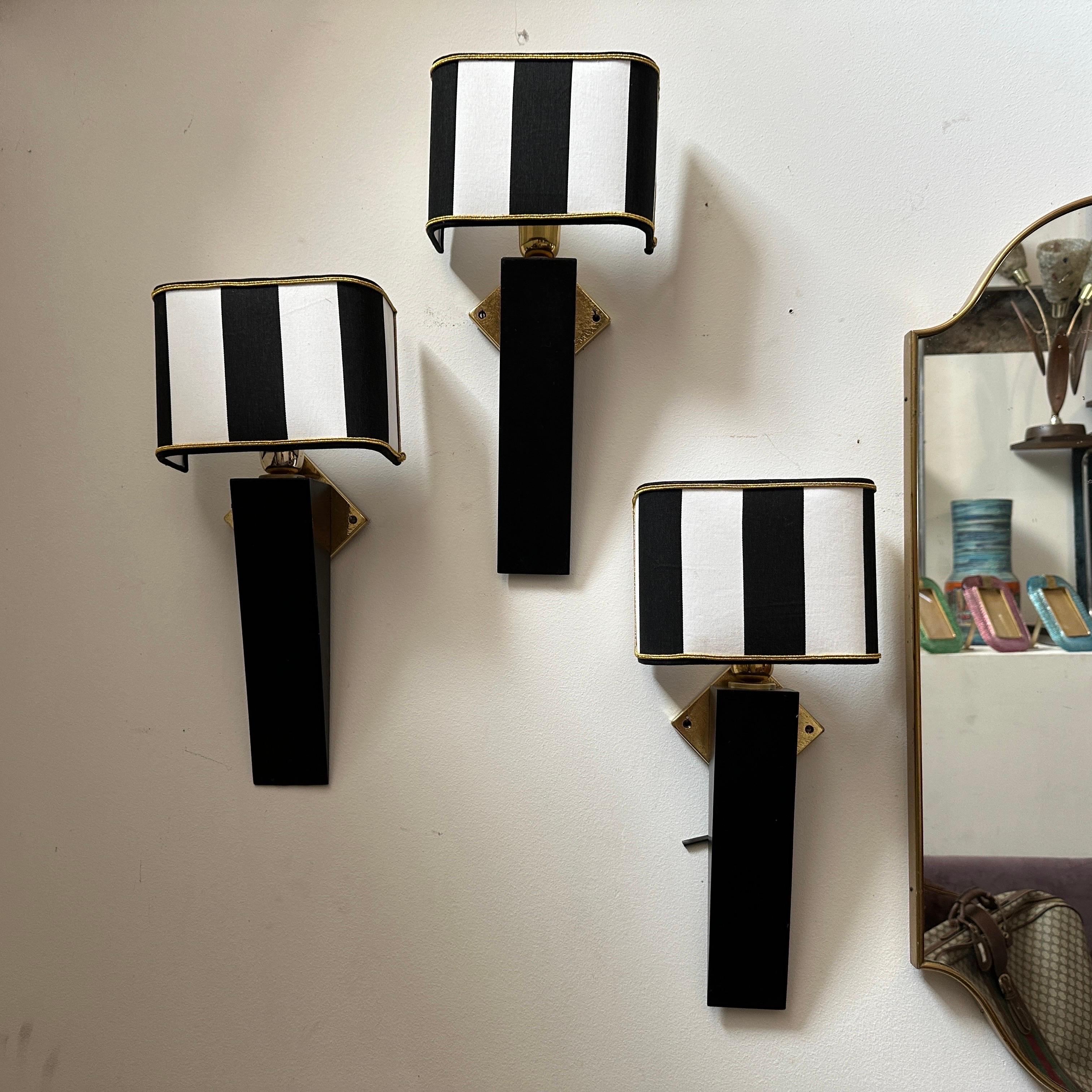 Diese italienische Wandleuchte im Art-Déco-Stil aus den 1980er Jahren besticht durch ihre schlichte und raffinierte Ästhetik. Der Sockel ist aus Holz gefertigt und für einen dramatischen und modernen Look in poliertem Schwarz