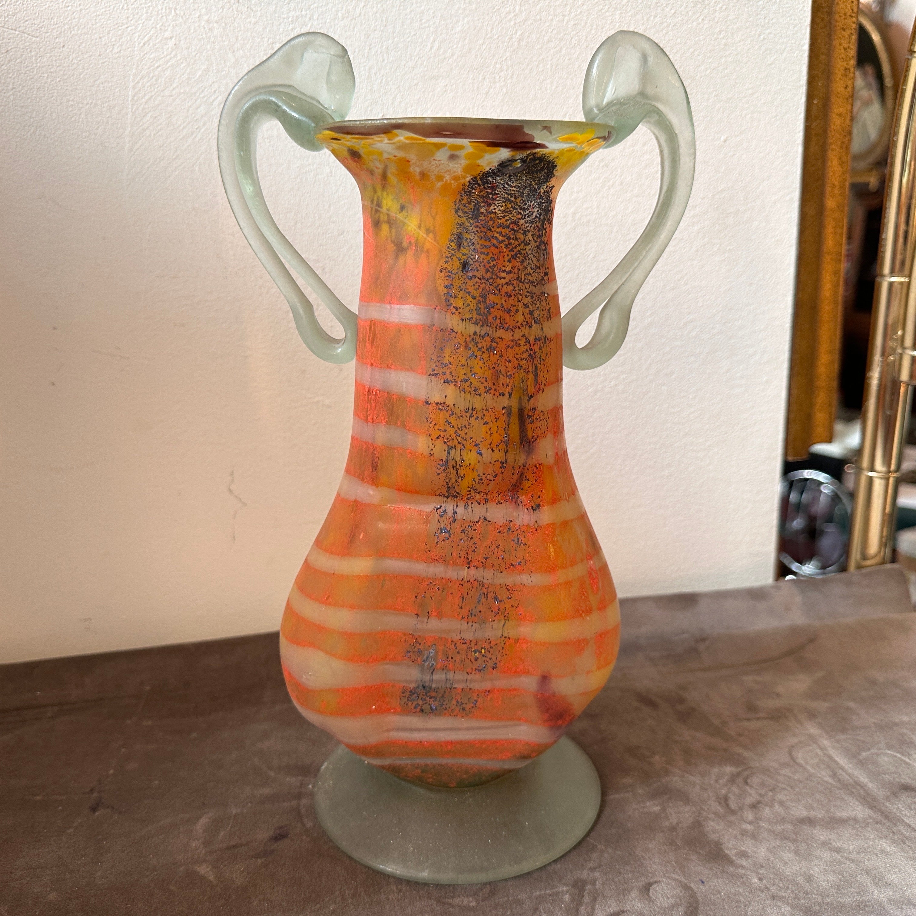 Questo vaso in vetro di Murano degli anni '80 è un esempio vibrante ed elegante di arte vetraria italiana. La combinazione di colori vivaci, la forma classica e i dettagli intricati ne fanno un pezzo forte. Sia che venga utilizzato come vaso