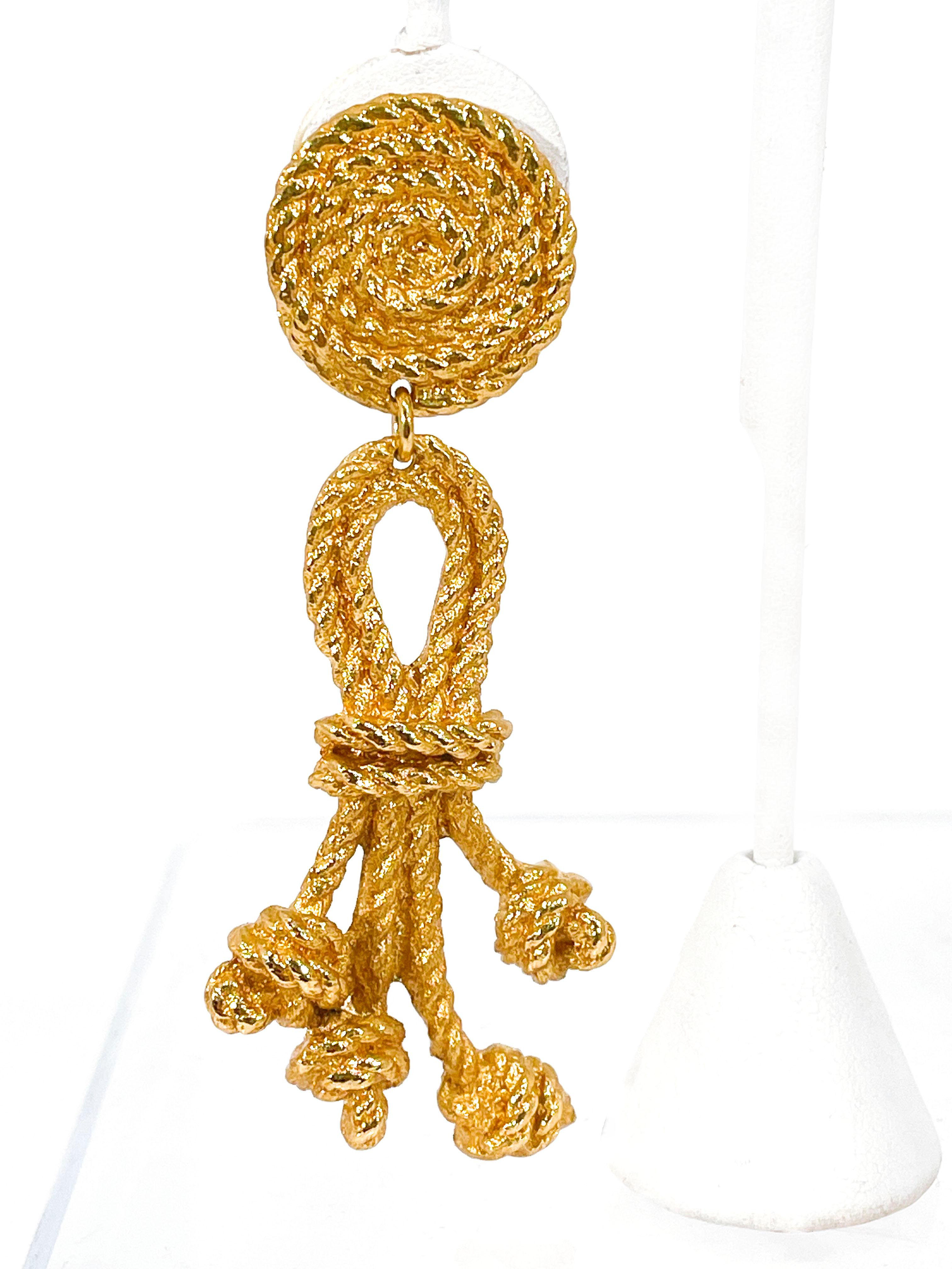 1980's Atalante (YSL) Rope & Knot motif clip-on drop earrings in a gilded gold tone metal. The rope and knot drop emphasizes movement while these earrings are worn. Atalante is an adjunct of the Yves Saint Laurent group, and the pieces in this line