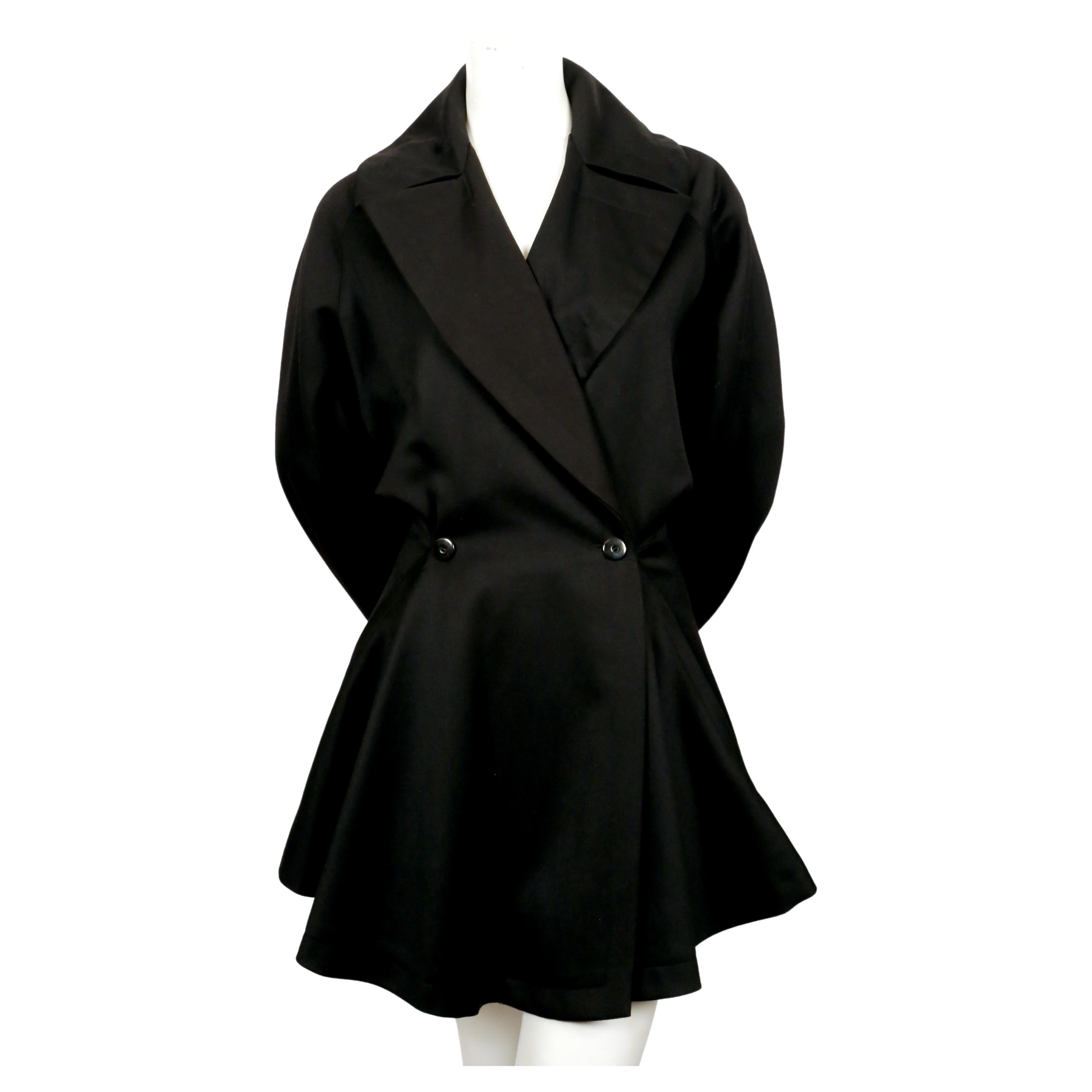 Jet-black, gabardine wool coat with full skirt and uniquely constructed cut out back designed by Azzedine Alaia dating to the late 1980's. Very flattering fit. Coat is labeled a French size 38. Approximate measurements: waist 28-29