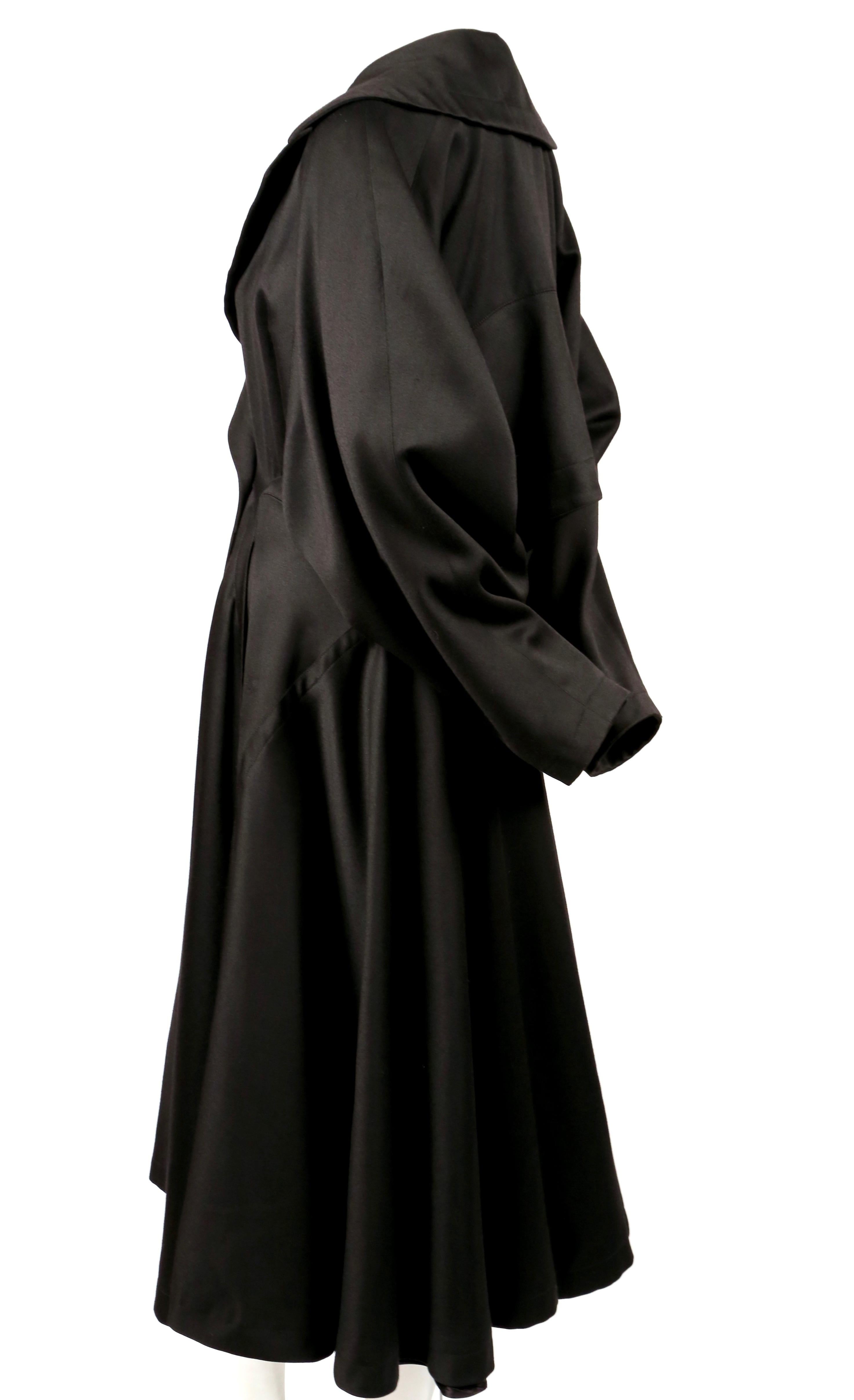 Jet-black, gabardine wool coat with full skirt and uniquely constructed back designed by Azzedine Alaia dating to the late 1980's. Very flattering fit. Coat is labeled a French size 38. Approximate measurements: waist 28-29