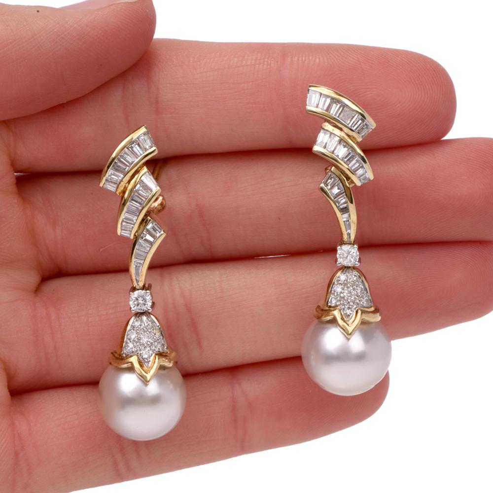 These stunning estate pendant earrings of alluring aesthetic are crafted in 14 karat yellow gold, incorporating each a lustrous white with a hue of pastel pink gray color South Sea pearl appox. 13mm  surmounted by tapered baguette diamonds capped by