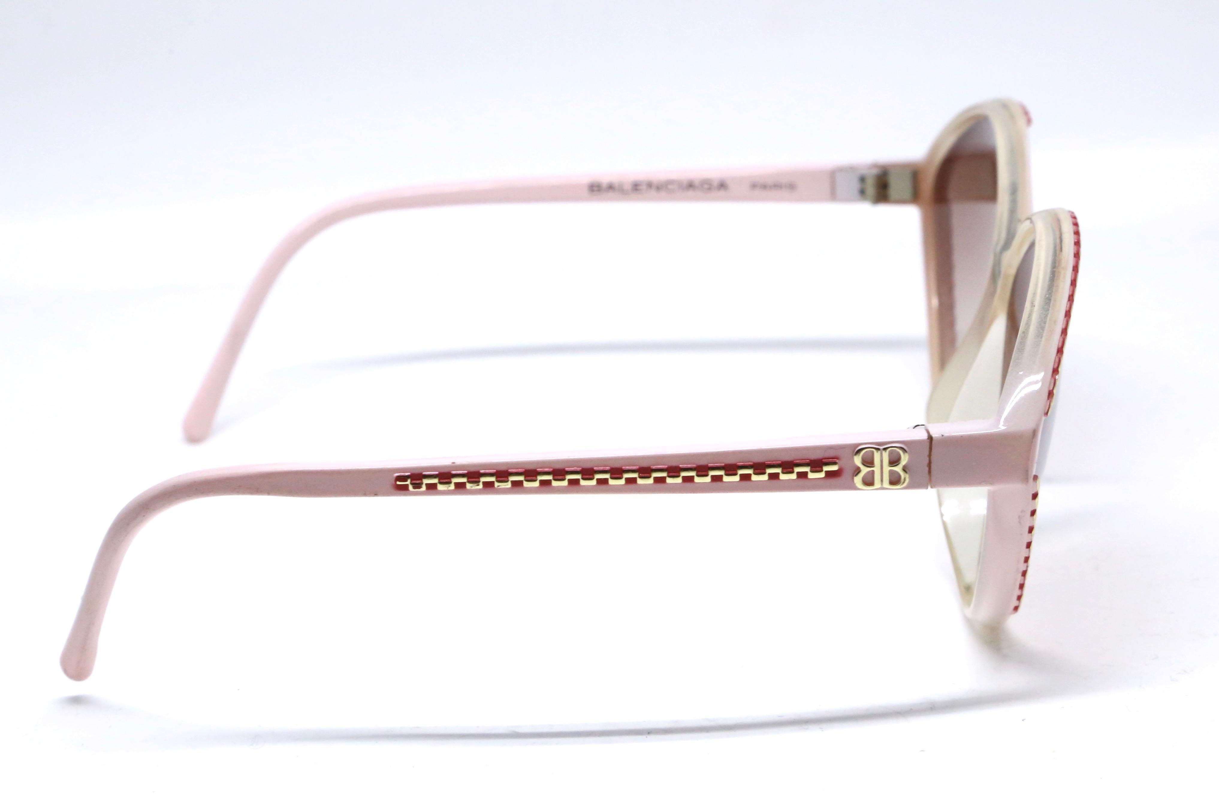 Unworn pink and burgundy plastic sunglasses with gold-tone accents from Balenciaga dating to the 1980's. Measures approximately: 150mm wide by 52mm tall. Made in France. New/old stock. Light wear/marks from storage.
