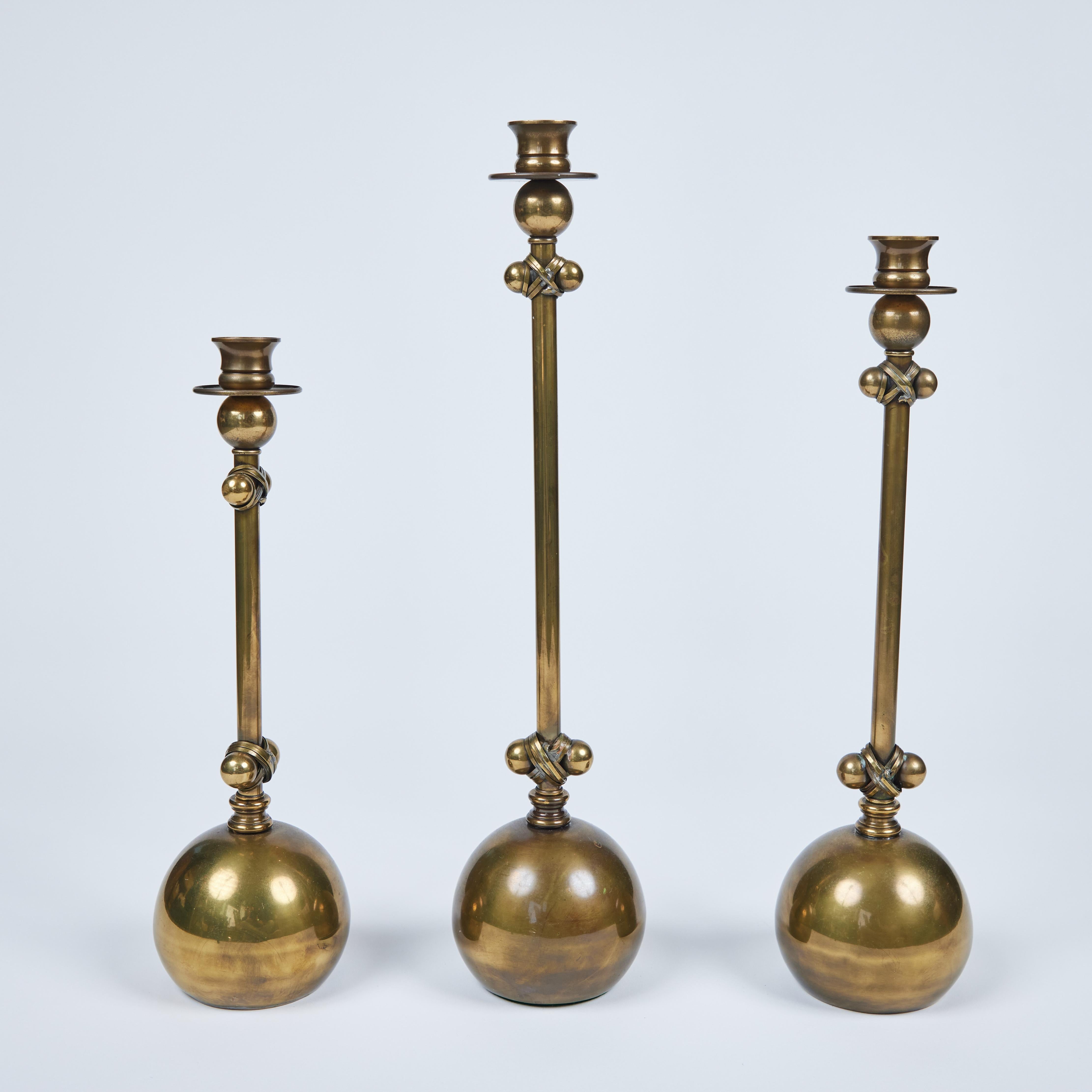 Tall and graceful this set of 3 - 1980's Ball Based Brass Candlesticks attributed to Chapman are truly stunning. They all have a similar sized bold brass ball base with the stem accents and come in 3 heights. They measure: tall 4.5