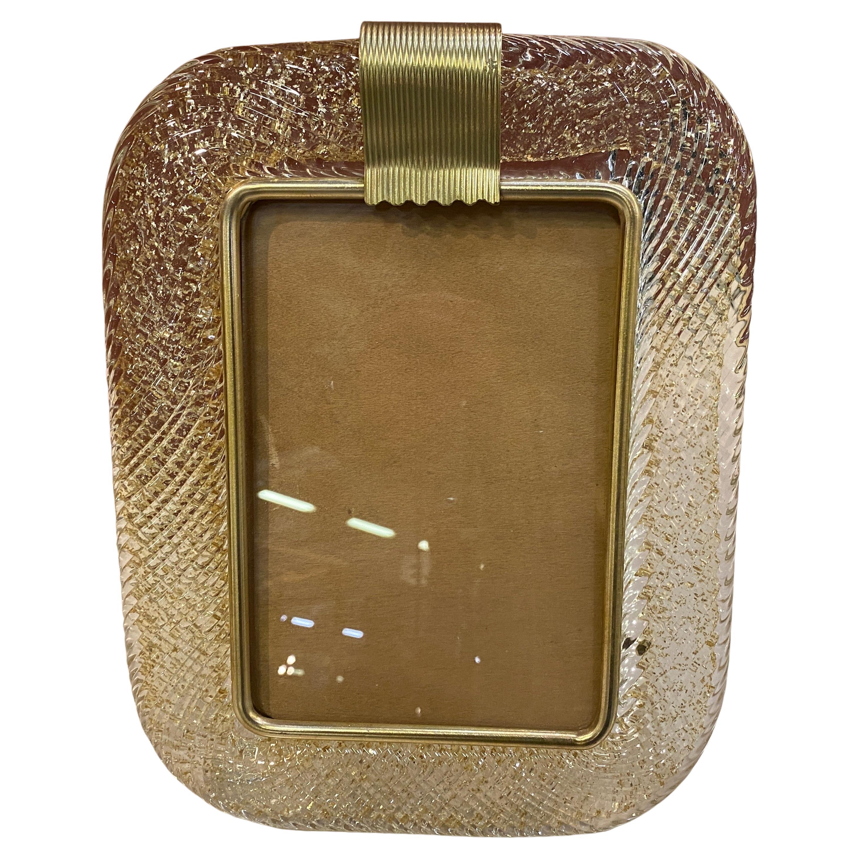 A Mid-Century Modern gold and transparent murano glass picture frame designed and hand-crafted in Venice, it's in good conditions overall, brass it's in original patina. It's an iconic Mid-Century Modern piece of the famous manufacturer Barovier.