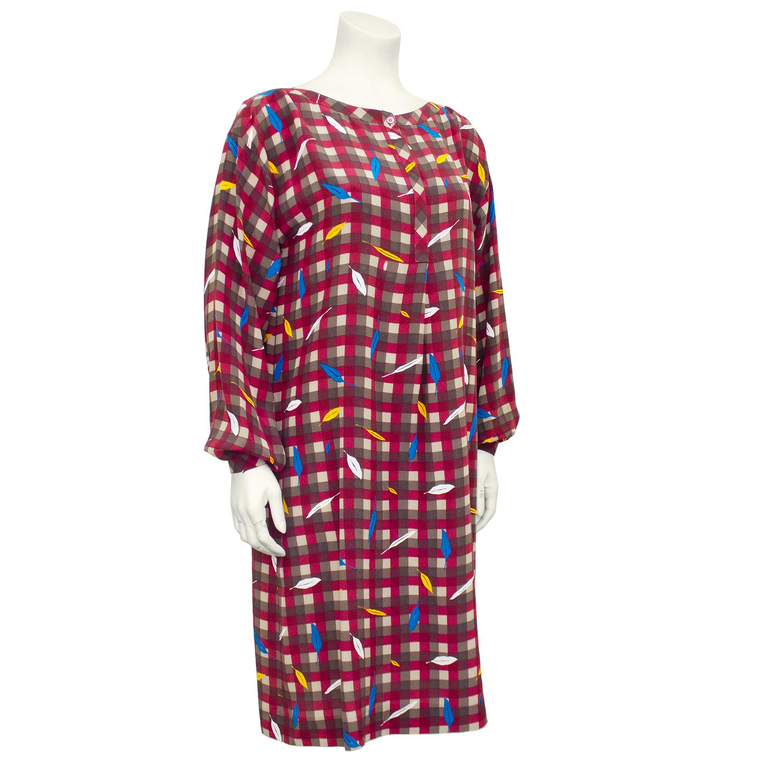 1980’s Basile silk dress. Maroon, olive and black all over check with cream, mustard and blue feathers throughout. Boat neckline and henley style button closure. Long bishop sleeves. Single inverted pleat at centre front. Perfect for fall. Excellent