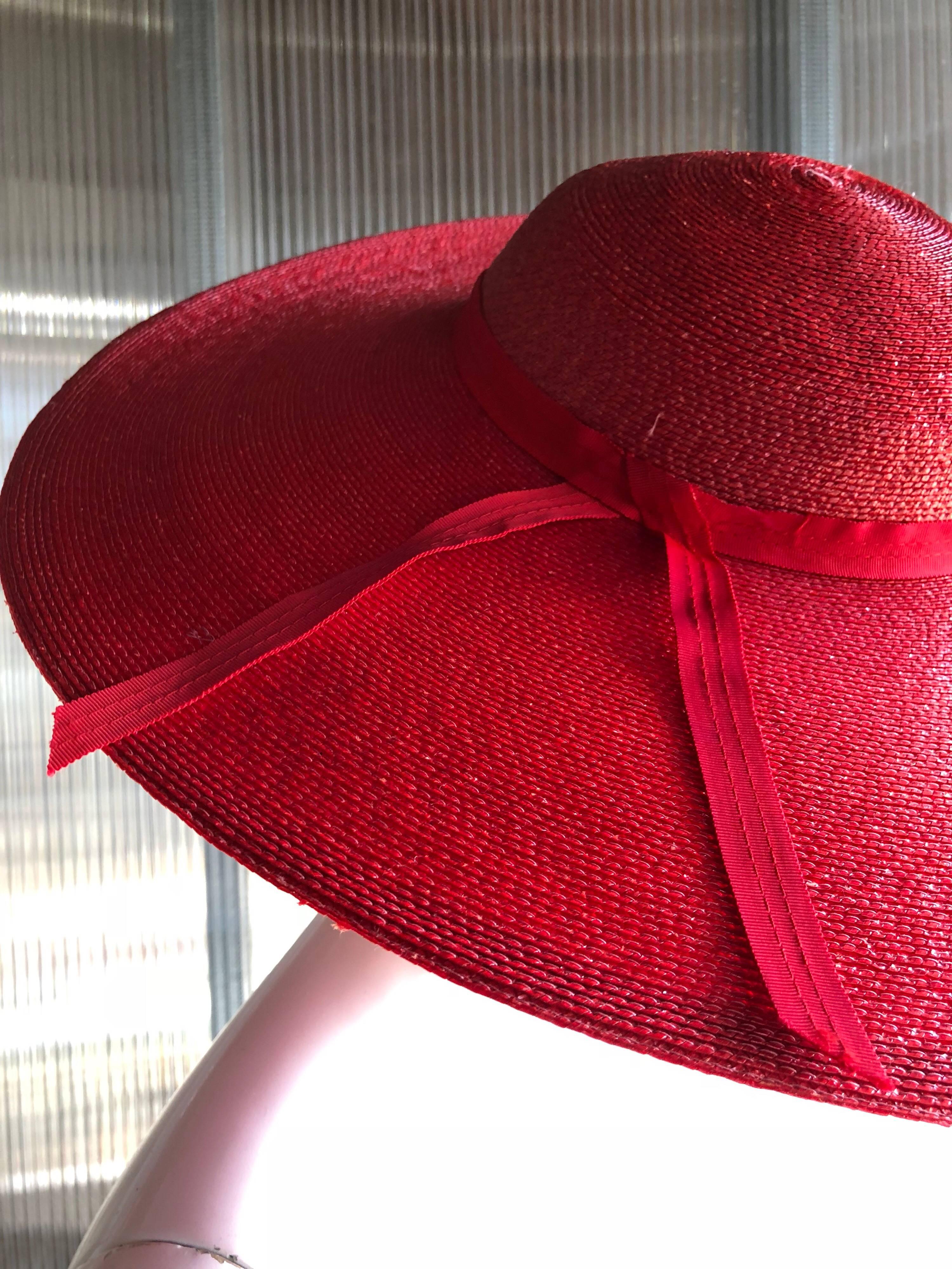 This 1980s red wide brimmed circular or saucer-shape design hat by Bellini Original features a low round crown. Typically, it is worn at an angel to show off the curve of the brim.
Woven in shiny red Milanese straw in a 1950s style revival 