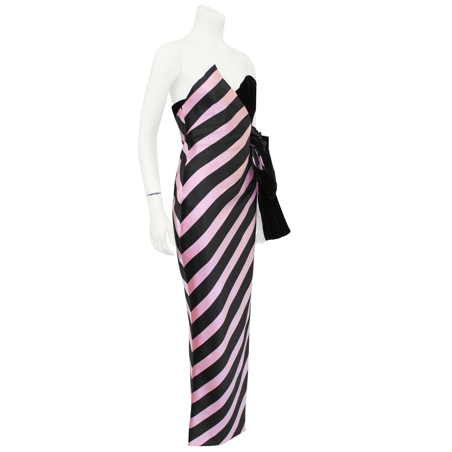 Bellville Sasoon black and pink strapless evening gown from the 1980s. The asymmetrical gown is half diagonally striped silk and half black velvet with a large black velvet bow and corsage. The gown's sweetheart neckline is pointed on one side and