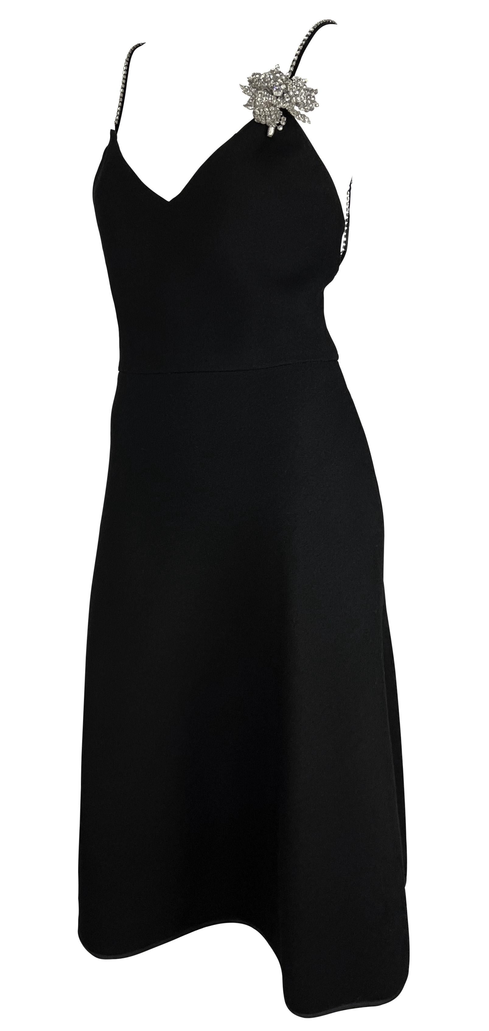 Cette fabuleuse robe midi noire de Bill Blass, datant des années 1980, est confectionnée en laine noire épaisse. La robe comporte des bretelles spaghetti rehaussées de strass et une applique florale en métal ornée de strass sur un côté. Il est