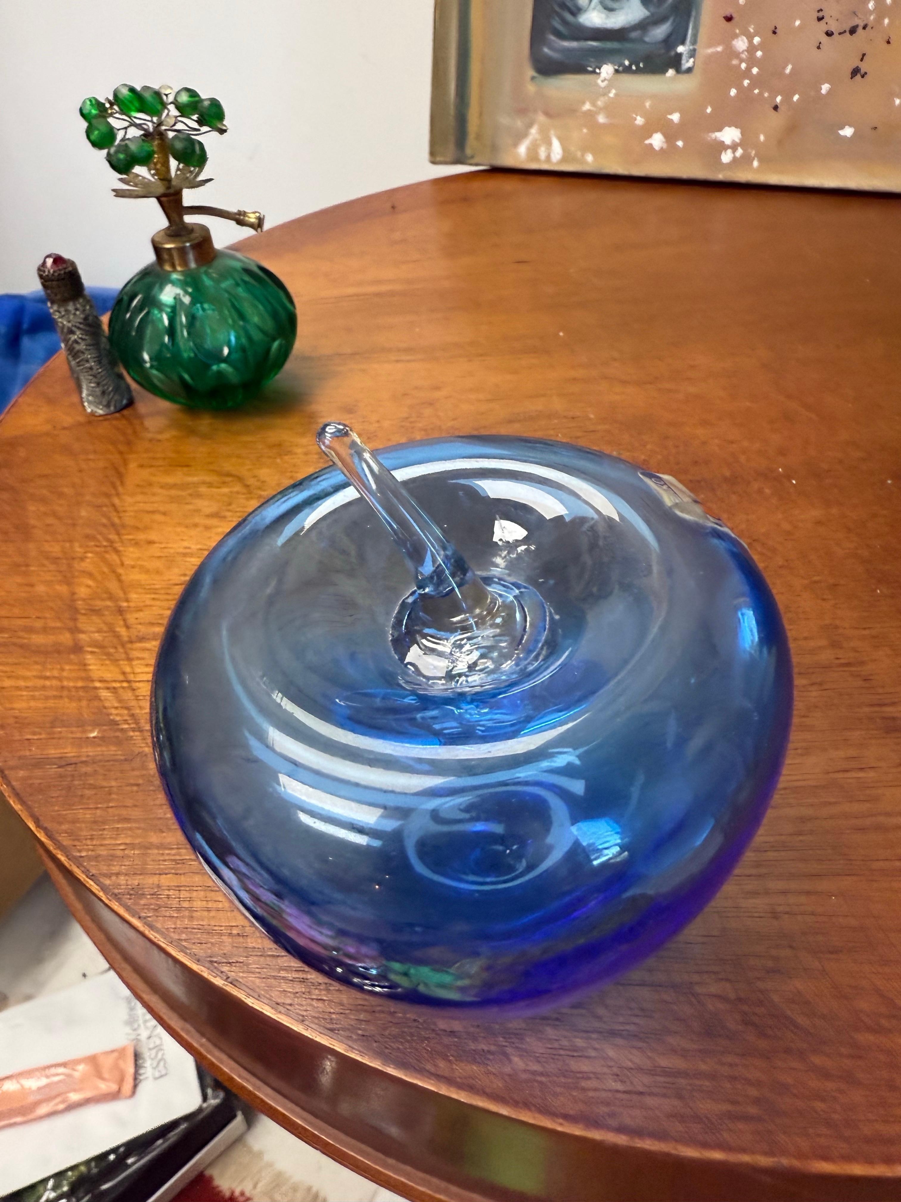 Una bellissima mela blu Blenko con gambo trasparente. Conserva ancora la sua etichetta originale. Questa grande mela soffiata a mano misura 4