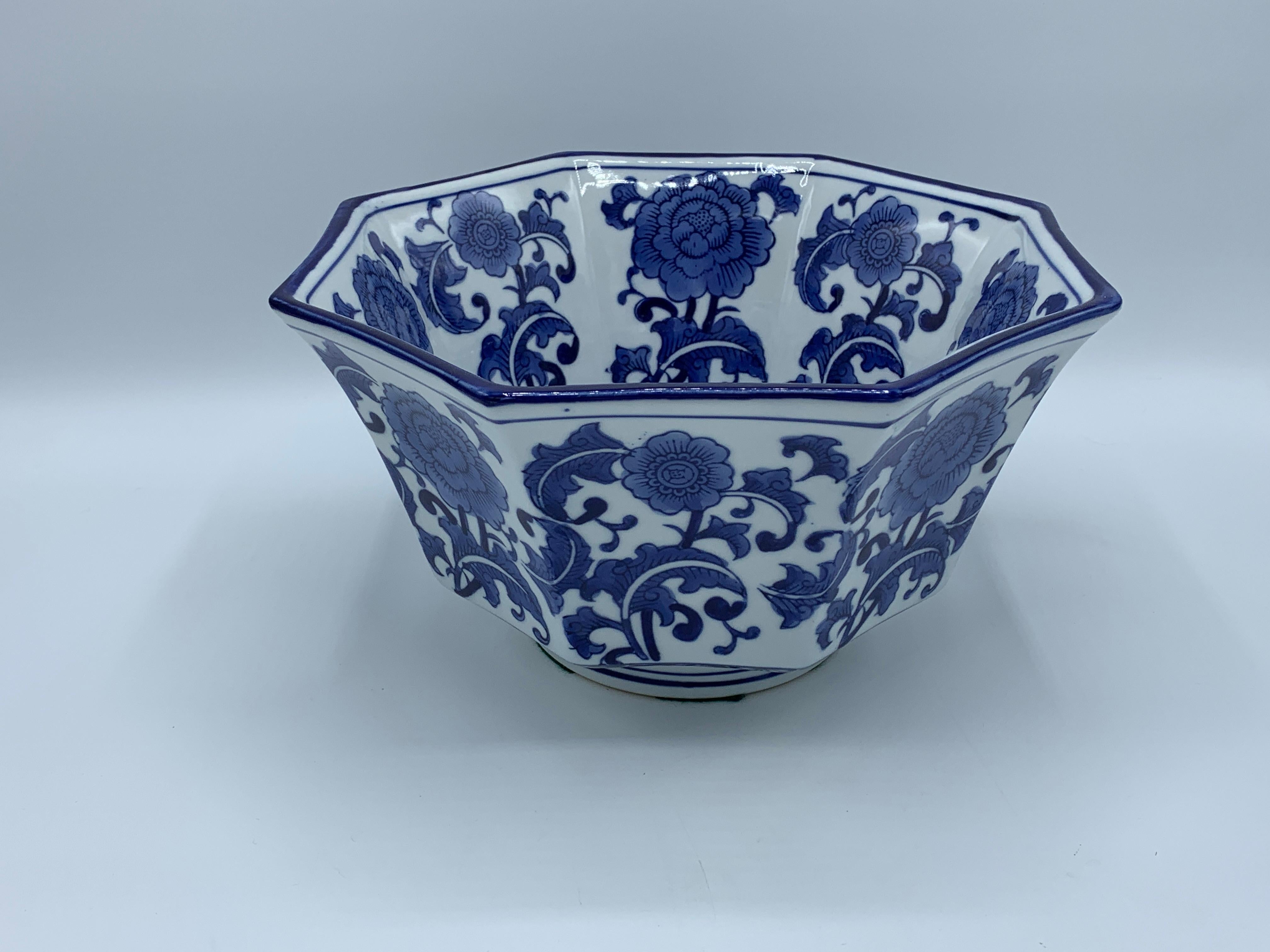 Listed is a gorgeous, 1980s blue and white porcelain bowl with a Chinoiserie peony and floral scroll motif. The bowl measures 10.5