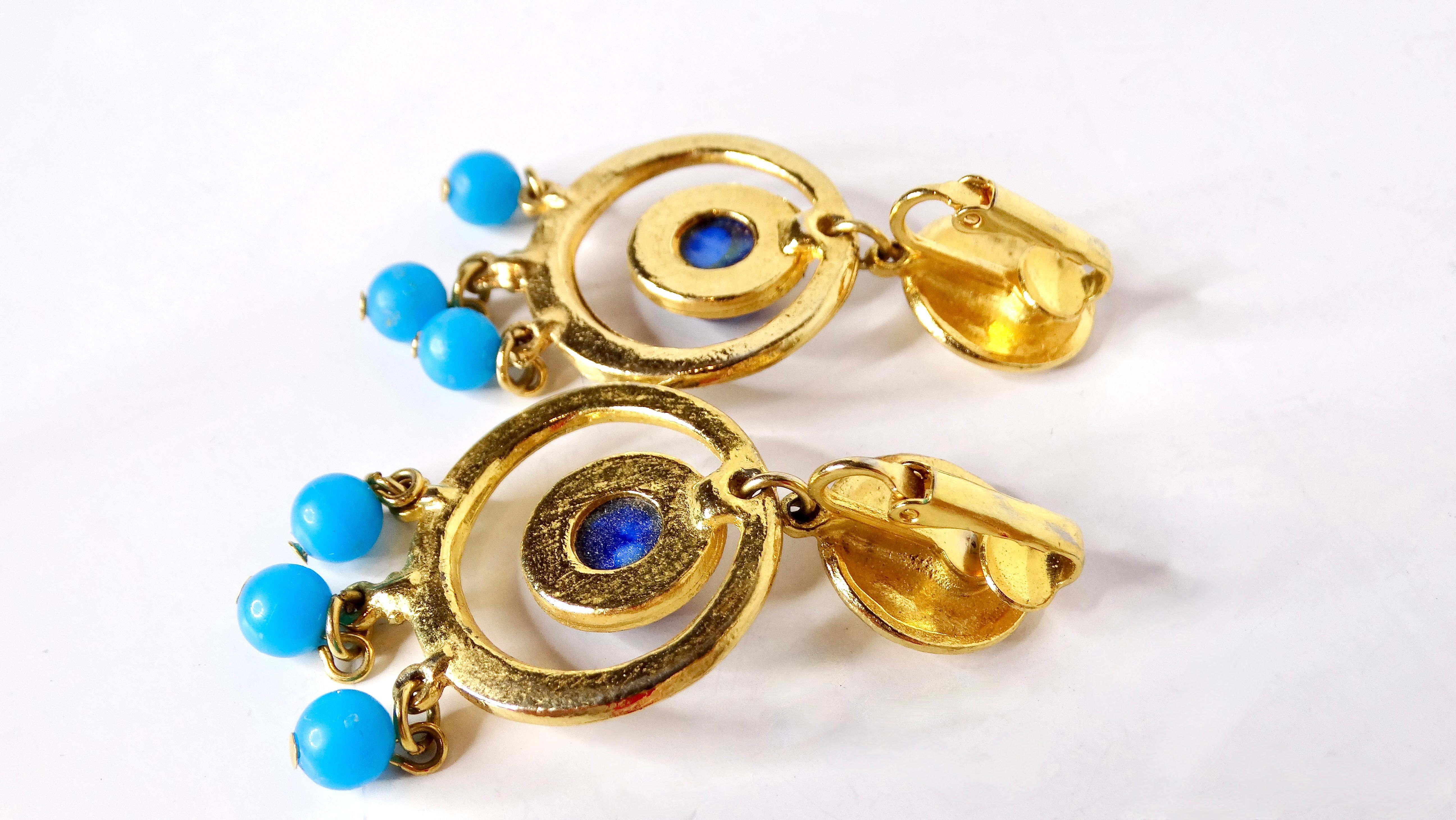 Elevate your accessory game with these stunning 1980s Blue Dangle Clip-On Earrings, crafted with an eye-catching dream catcher motif. These earrings feature an exquisite costume blue stone at their center, surrounded by delicately hanging blue beads