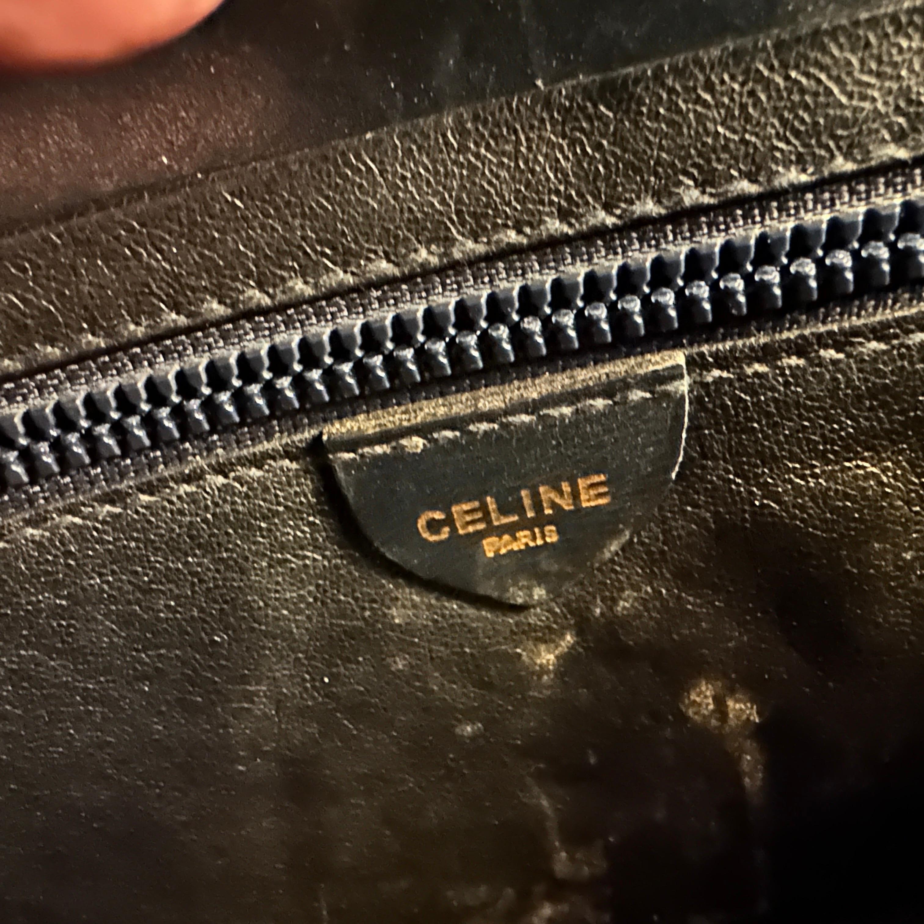 This is a vintage Céline pochette clutch bag from the 1980s, crafted from deep blue leather with a smooth, polished finish. The bag features a structured envelope-style silhouette with a sharp, angular flap. The standout detail is the gold-tone