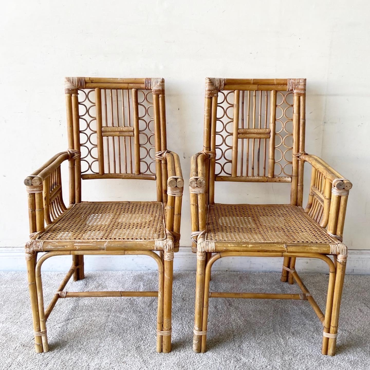 Phenomenal pair of vintage bohemian bamboo and rattan dining chairs. Each feature a can seat with a fretted back rest.
 