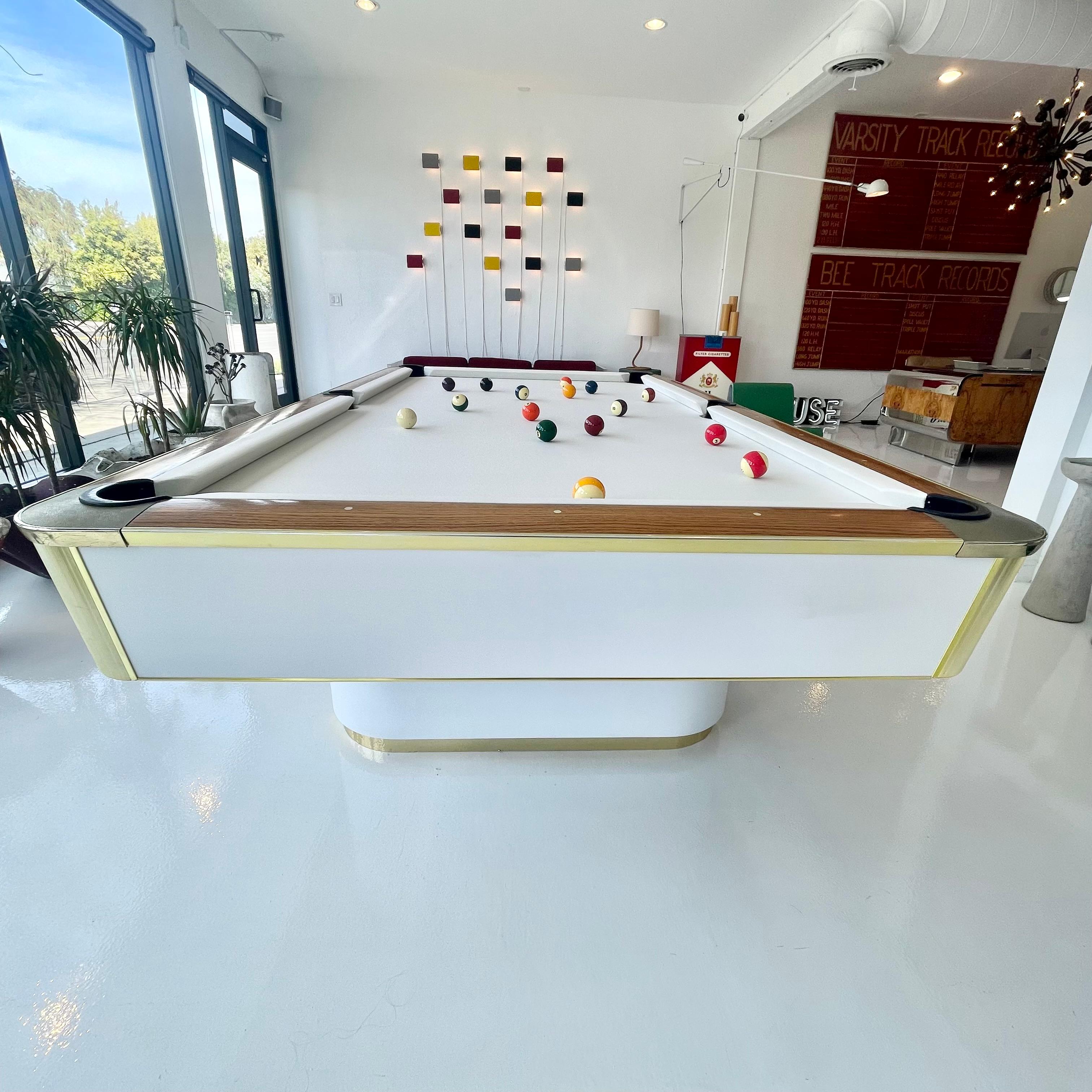 Elegant snow white and golden brass 1980s pool table by Murrey. Made in Los Angeles. Mother of pearl markers inlaid in Maple edges. Excellent condition to Formica panels. Beautiful dual pedestal design with brass trim, give this table a floating
