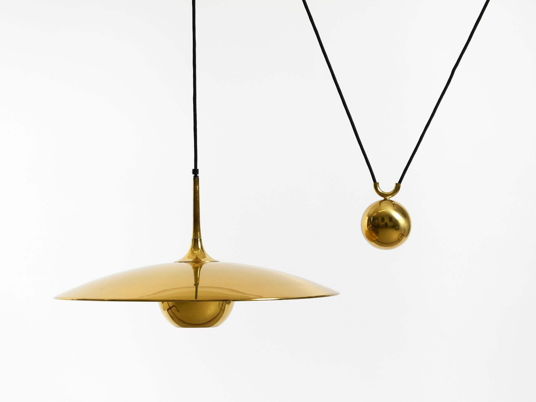 Grande lampada a sospensione originale Florian Schulz Onos 55 degli anni '80, regolabile in altezza con un contrappeso. La lampada è realizzata interamente in ottone.
Bellissimo design minimalista in ottime condizioni vintage con una patina