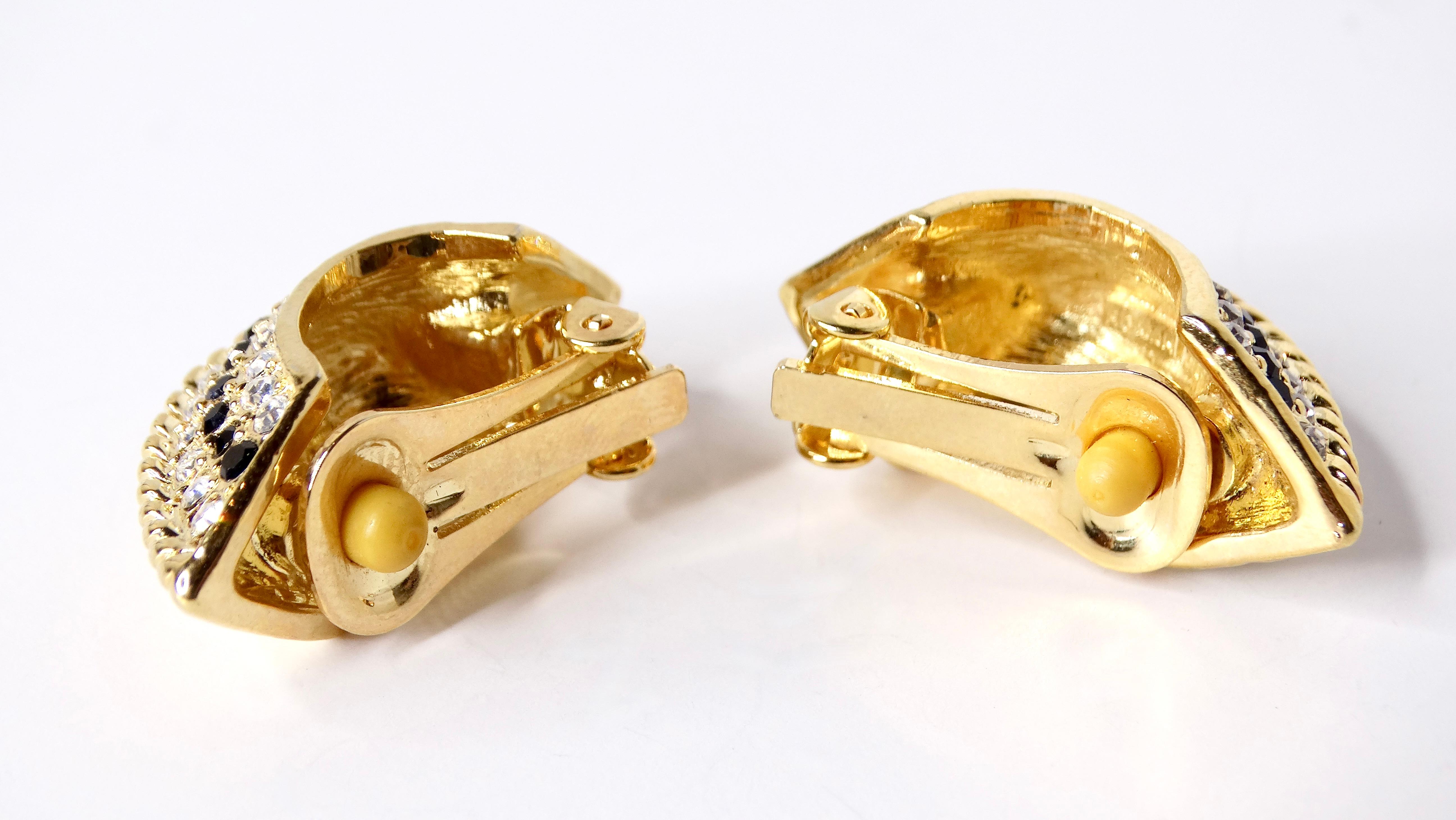 Entrez dans l'opulence des années 1980 avec ces boucles d'oreilles incrustées de cristaux fantaisie d'inspiration bulgare, conçues dans une forme demi-hublot étonnante. Ornées d'un éventail de strass éblouissants, ces boucles d'oreilles évoquent une