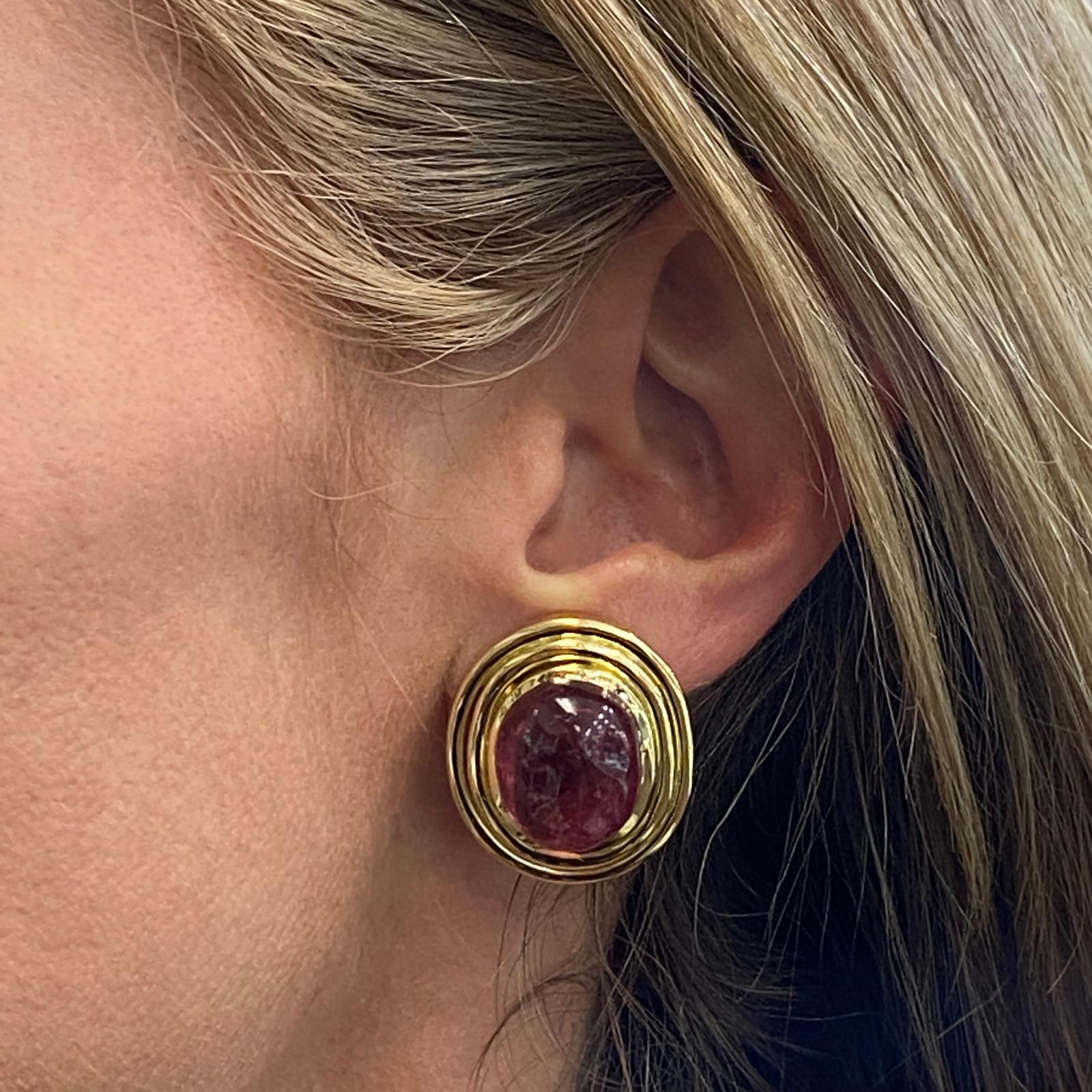 Beautiful pink rubelite earrings fashioned in 18 karat yellow gold by English designer Leo DeVroomen. The earrings feature oval cabochon rubelite pink gemstones set in ribbed 18 karat yellow gold. The earrings are clip backs, measure 20 x 28mm. and