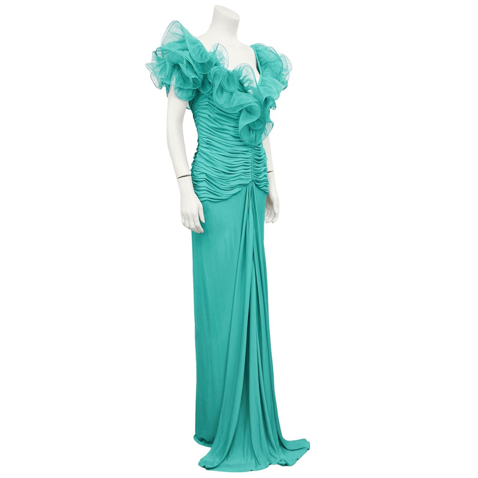 1980s Candice Fraiberger turquoise jersey gown. Stunning v neckline with layered ruffle shoulders and ruching throughout bodice. Drop waist with floor length skirt featuring draping down centre that falls beautifully and pools on the ground. Marked