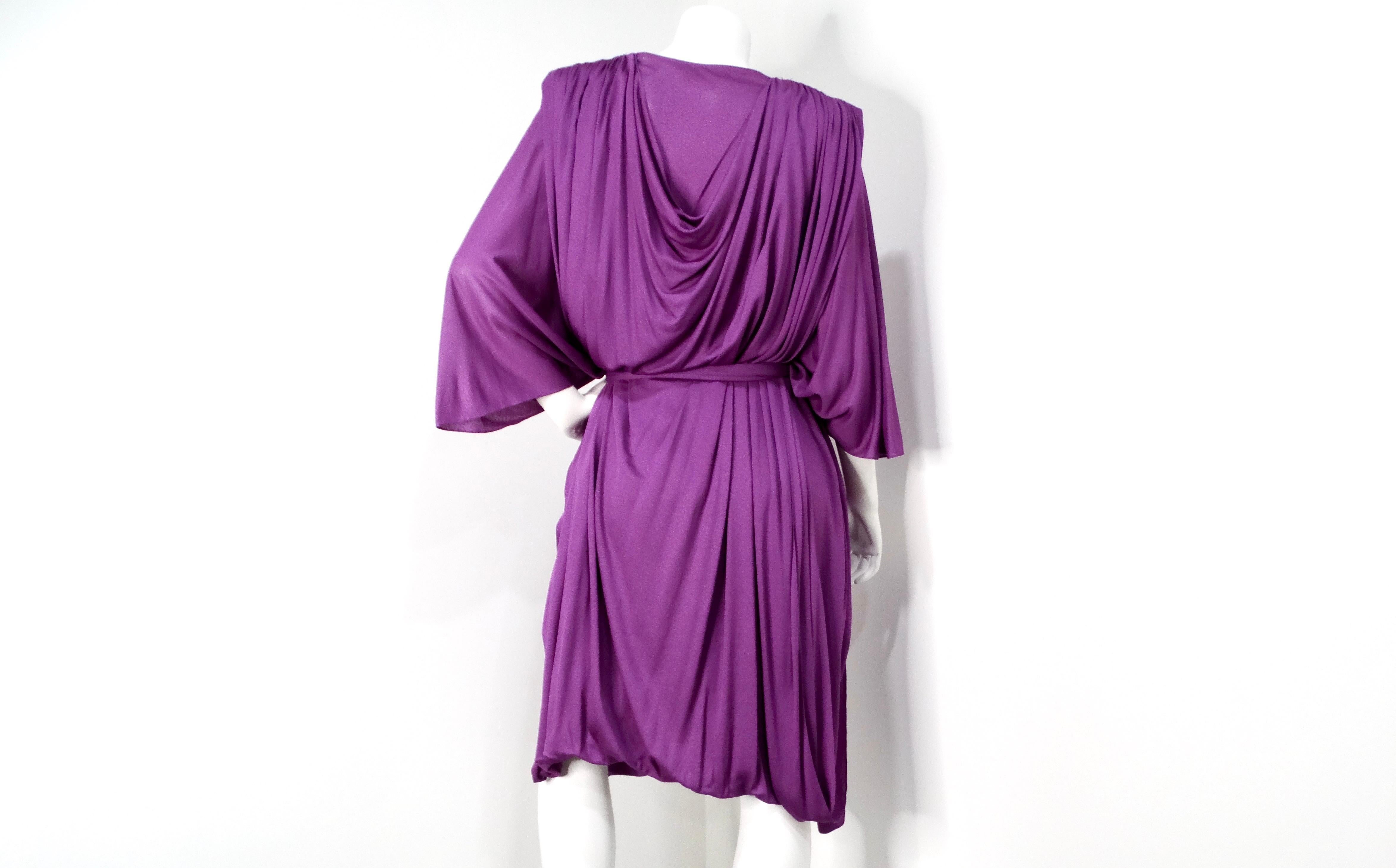 The 1980s Capriccio Italian Made Purple Toga Belted Dress is a stunning piece that encapsulates the bold and expressive fashion sensibilities of the decade. The dress features a unique toga-inspired design that flows gracefully around the body,