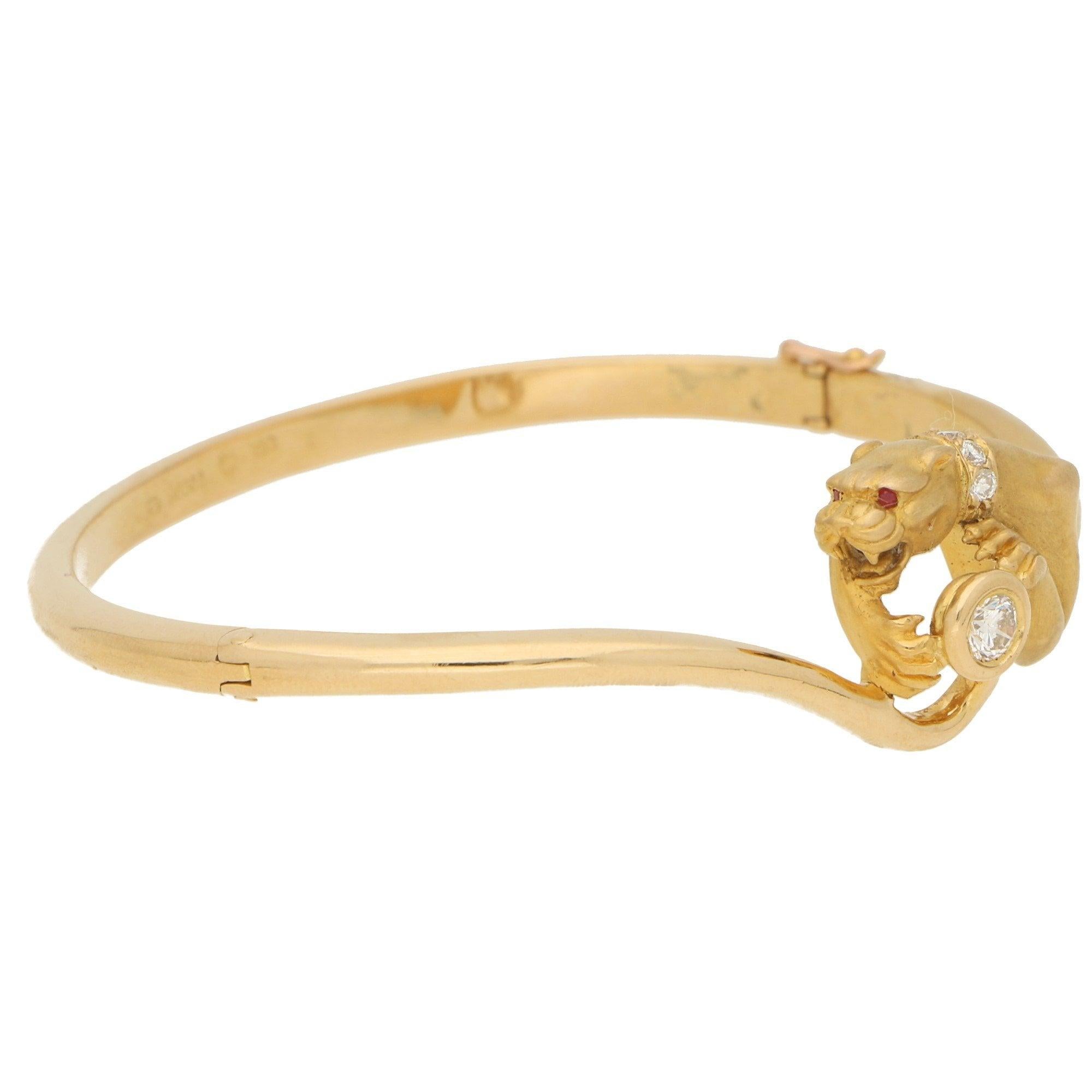 A vintage Carrera y Carrera diamond panther bangle bracelet in 18-karat yellow gold, circa 1980. This piece is depicted as a panther pouching on a collet-set round brilliant-cut diamond, further accented with a round brilliant-cut diamond collar and