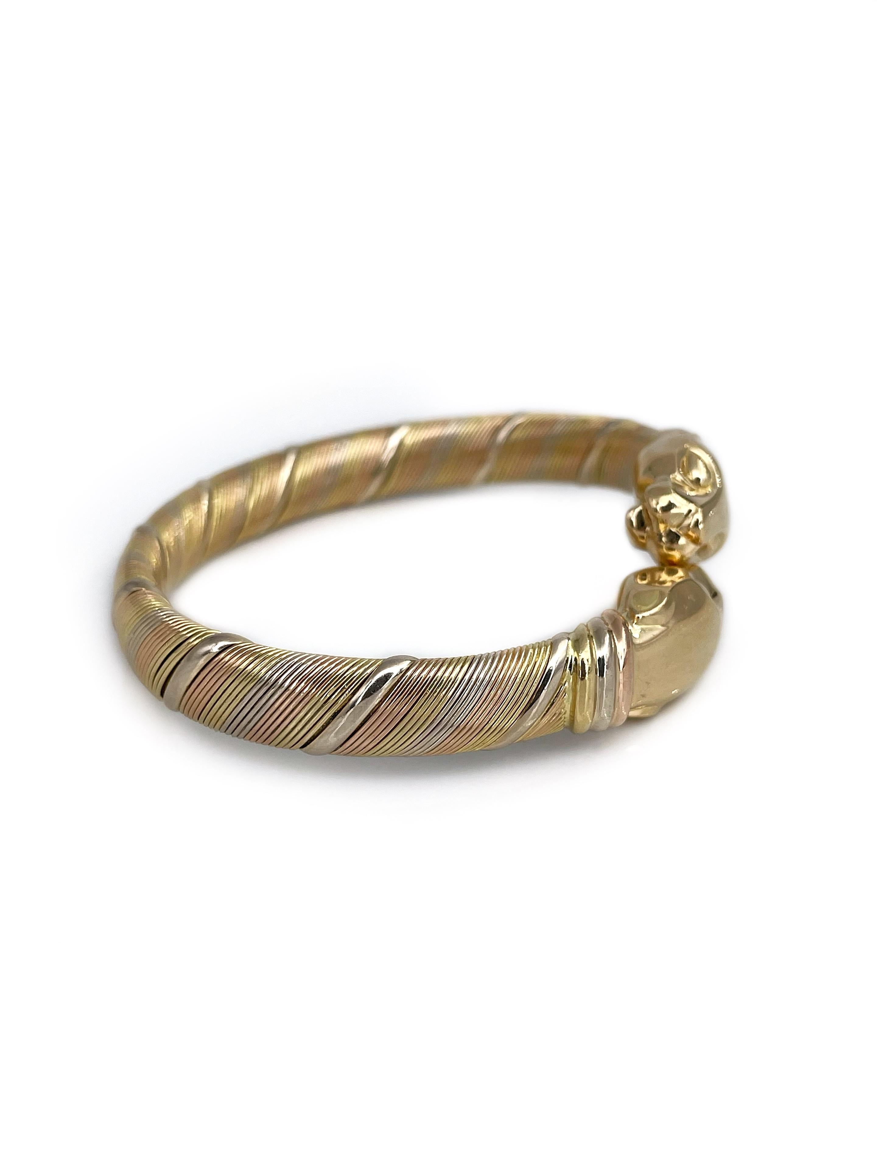 This is a stylish vintage double headed panther cuff bangle bracelet designed by Cartier in 1980s. It is crafted in 18K tri-color (rose, white and yellow) gold. The piece is half flexible which makes it quite easy to put on and off the wrist.