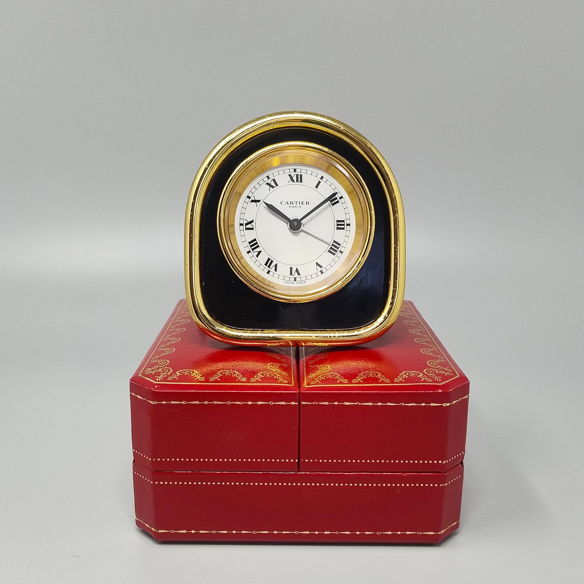 1980s Gorgeous Cartier in art deco style alarm clock pendulette. Made in Swiss. It's in 24K gold plated , black enamel  metal and white enamel dial with roman numbers. Manual charge 8 days movement. Designed in the 1920s, this Cartier alarm clock