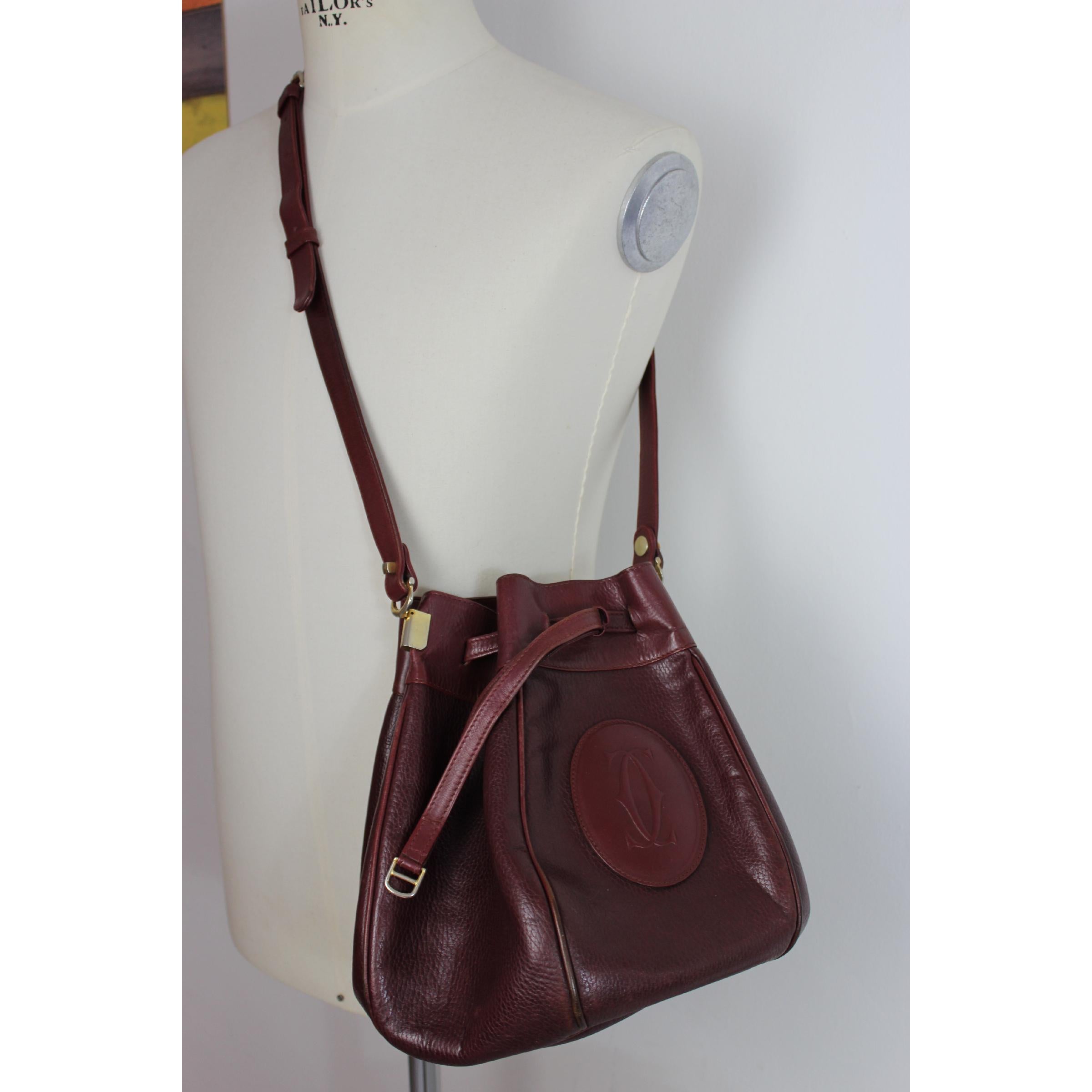 Must De Cartier vintage women's shoulder bag, burgundy color, 100% leather, bucket model, adjustable lace-up closure, internal dividers. 80s. Made in Italy. Excellent vintage condition.

Width: 38 cm
Height: 26 cm
Depth: 22 cm