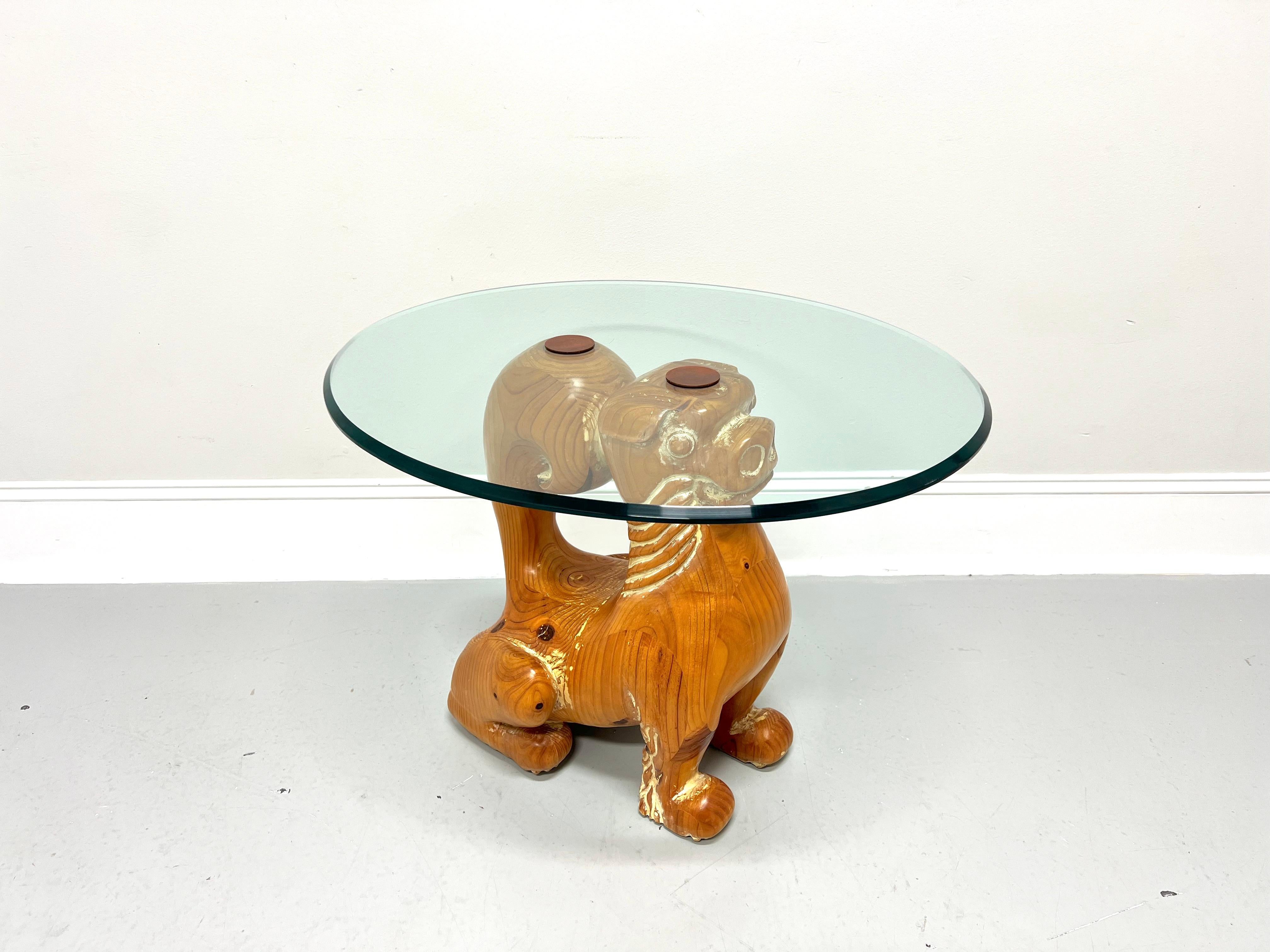 An Asian style glass top accent table, unbranded. Solid pine base with a distressed whitewash finish carved in the form of a Foo Dog Guardian Lion with head and tail having a flat surface to support an oval shaped ogee edge glass top. Glass top
