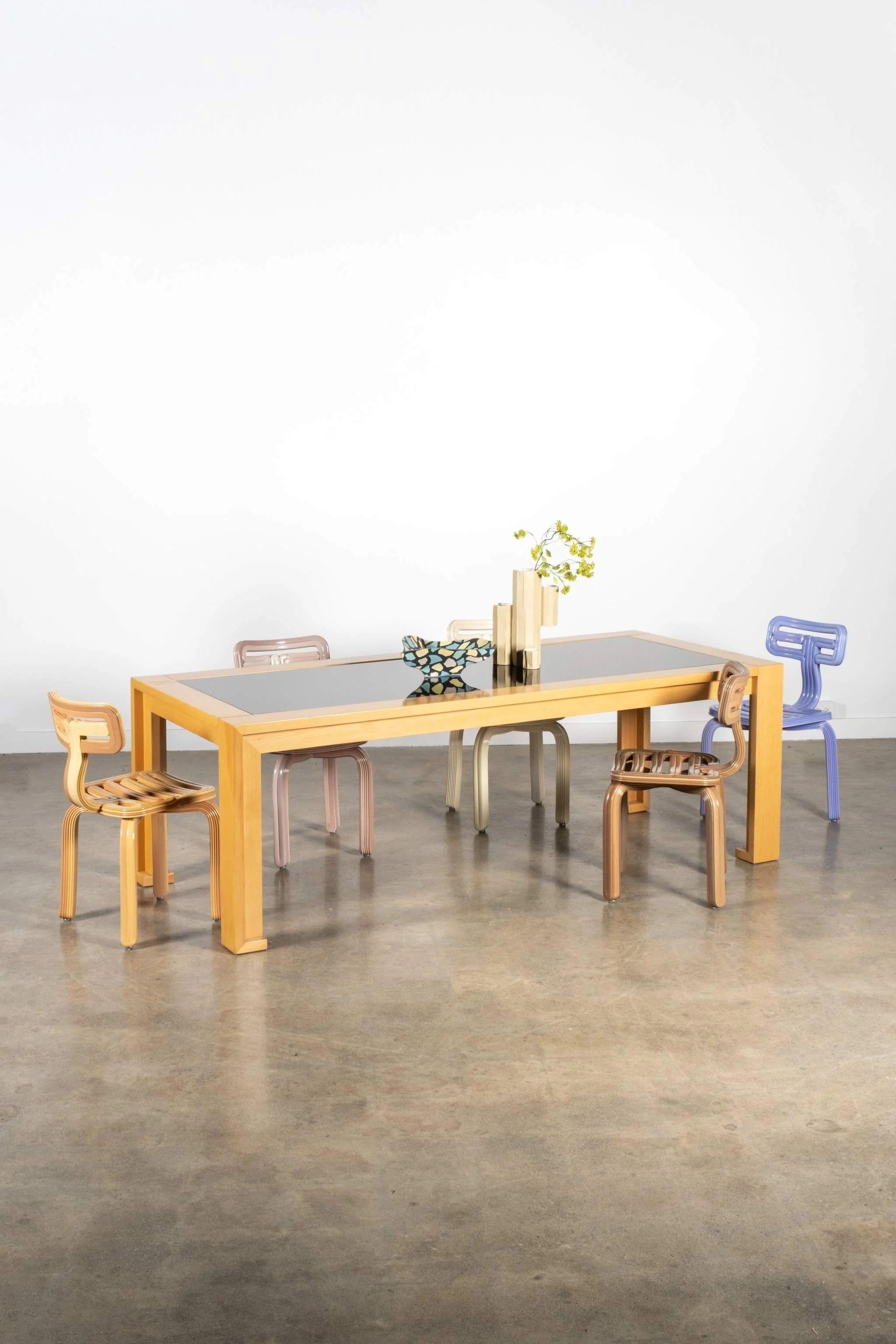 Conçue par Afra Scarpa pour Cassina dans les années 1980, cette table est un exemple rare de l'artisanat italien dans ce qu'il a de plus assuré. Un plateau en verre noir repose sur un cadre en bois de couleur miel, créant un jeu saisissant de