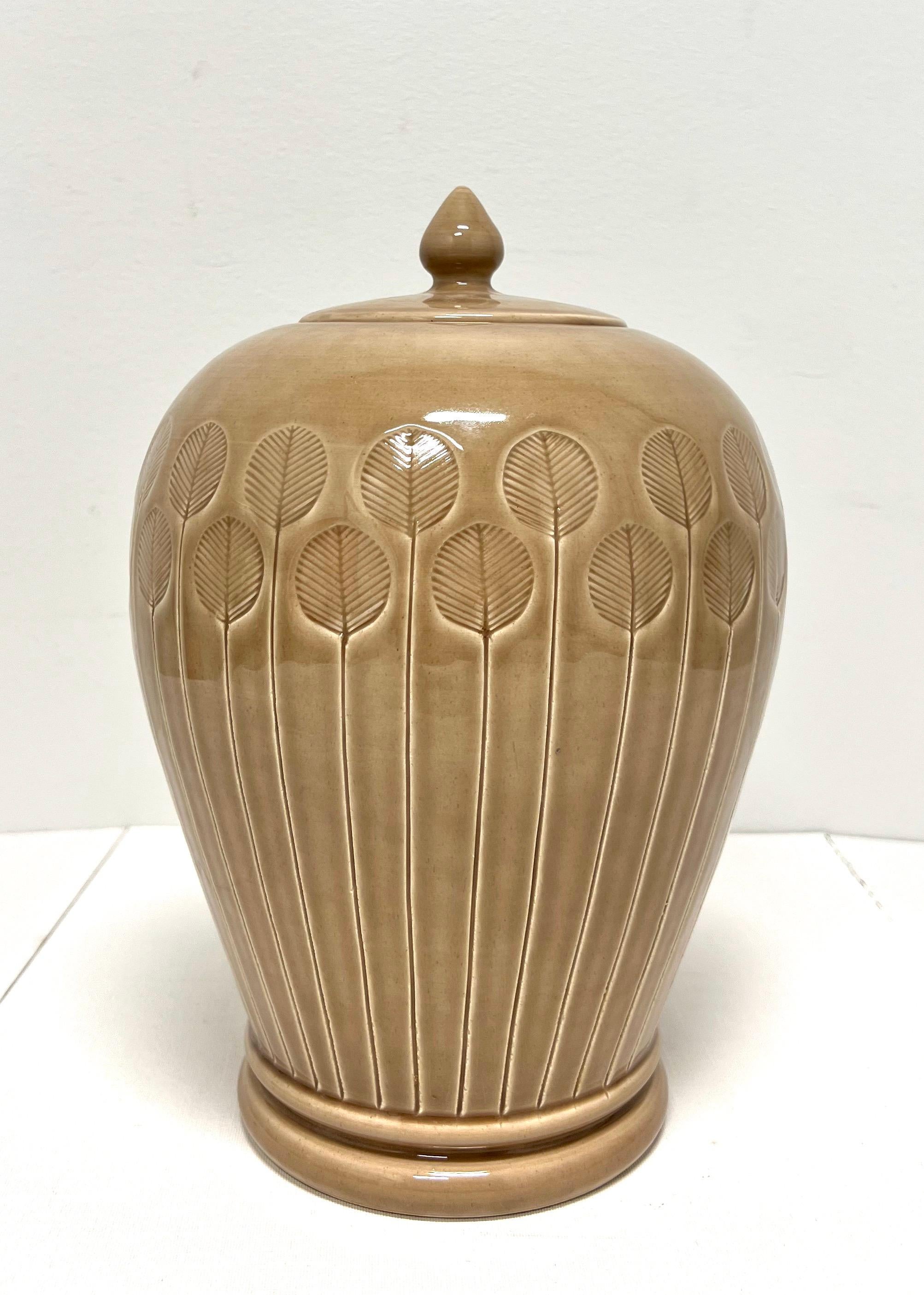 An Abstract Modern style ceramic ginger jar with lid, unbranded. Light brown in color, urn shaped, abstract flower design throughout and a small round handled lid. Likely made in China, circa 1980's.

Measures:  8w 8d 12h, Weighs Approximately: 6