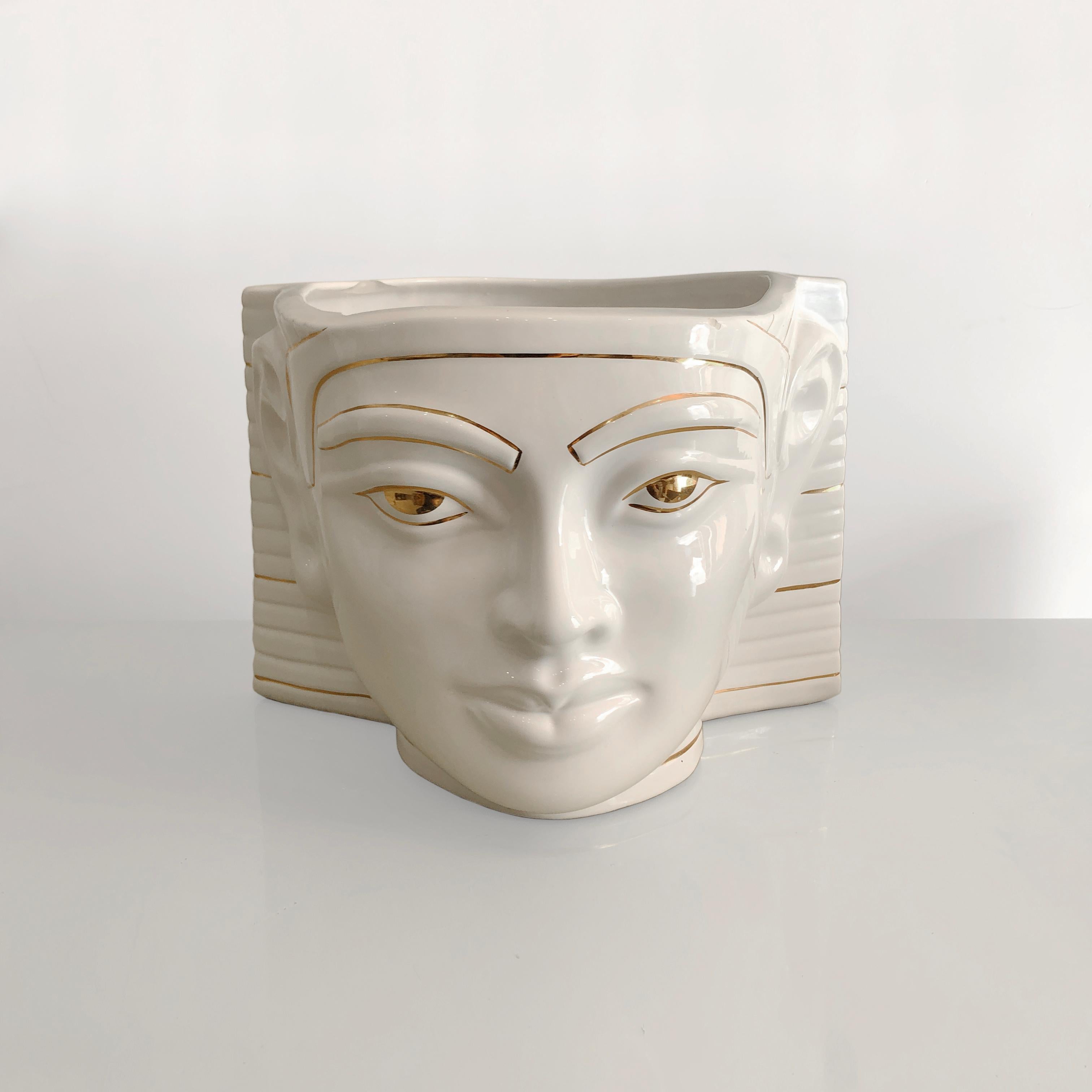 This Egyptian inspired ceramic glazed planter by Antica Athena consists of a white Pharaoh’s face with gold plated detailing. The Pharaoh's face brings to mind the Egyptian revival of the Art Deco period; an era which came about due to the sheer