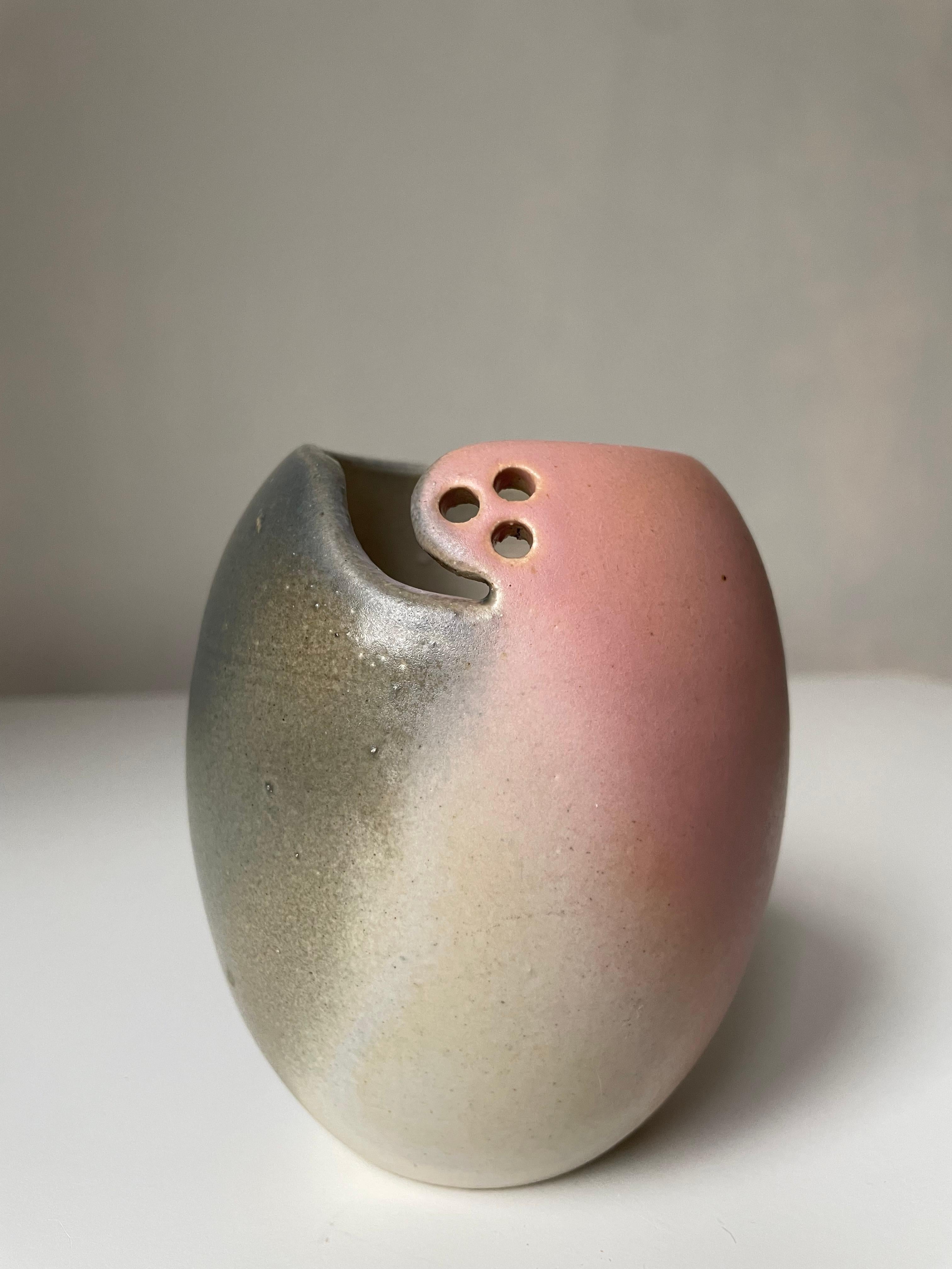 Vase en céramique artisanale en forme de tonneau, émaillé rose, pêche, blanc et gris foncé, avec décor perforé et sommet asymétrique. Estampillé sous la base. Belle condition vintage. 
Danemark, années 80. 