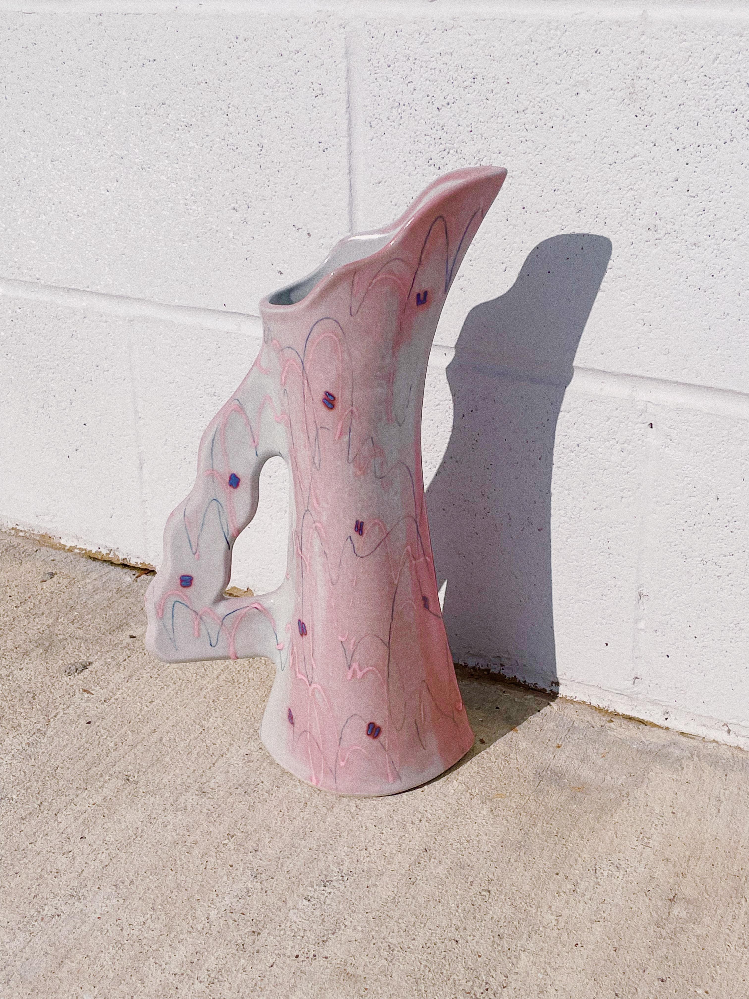 1980s Ceramic Sculptural Vase by Ingrid, Signed

Handcrafted from glazed ceramic, this vase features a unique, speckled pattern of pink and blue-gray hues with a soft, wavy handle and opening. This vase is able to accommodate a small selection of