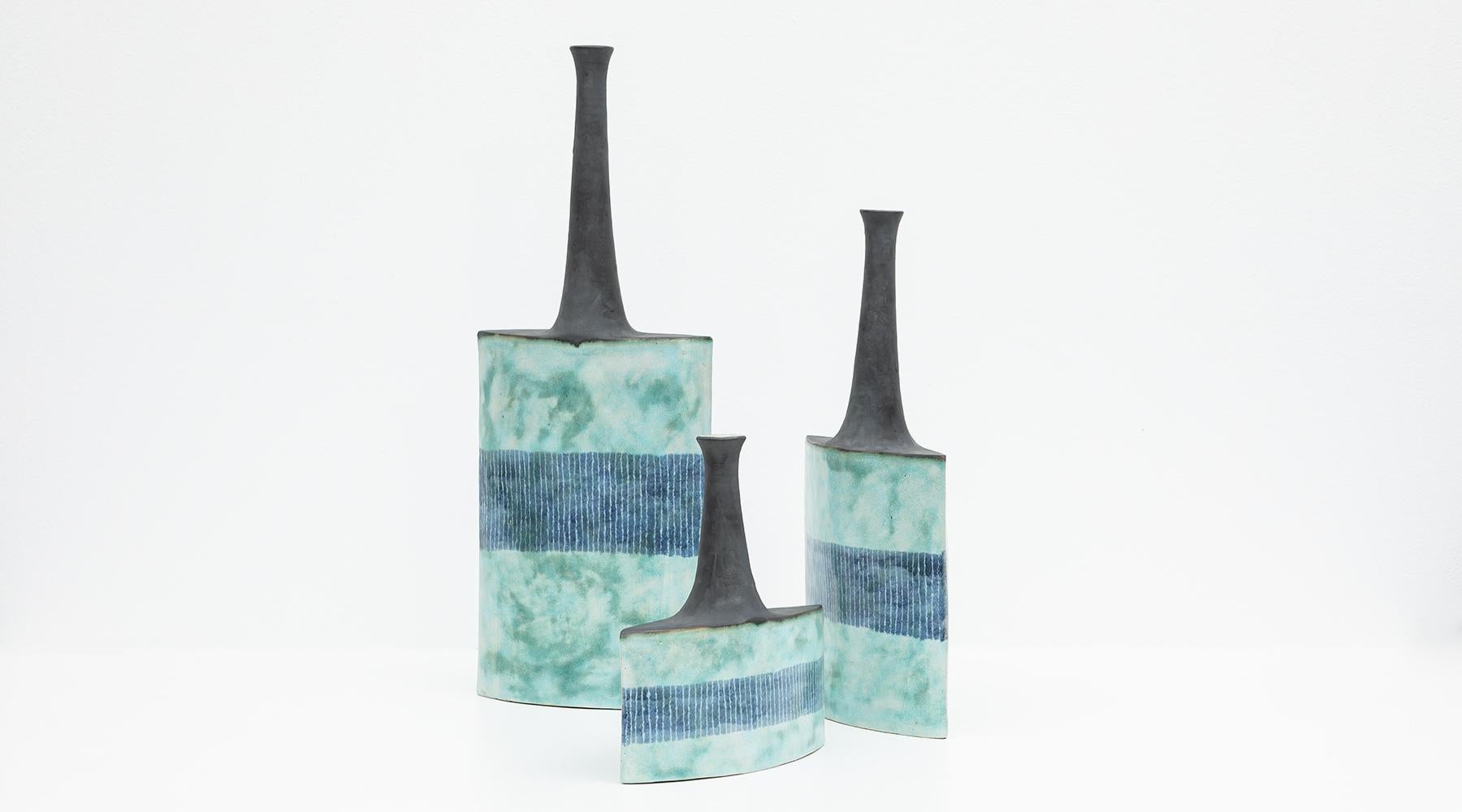 Set of three vases, ceramic, Bruno Gambone, Italy, 1980s.

Lovely set of three vases by the multi-talented artist Bruno Gambone from 1980s, varying in height but always the same width. Each vase comes with a long matte black neck, the body in
