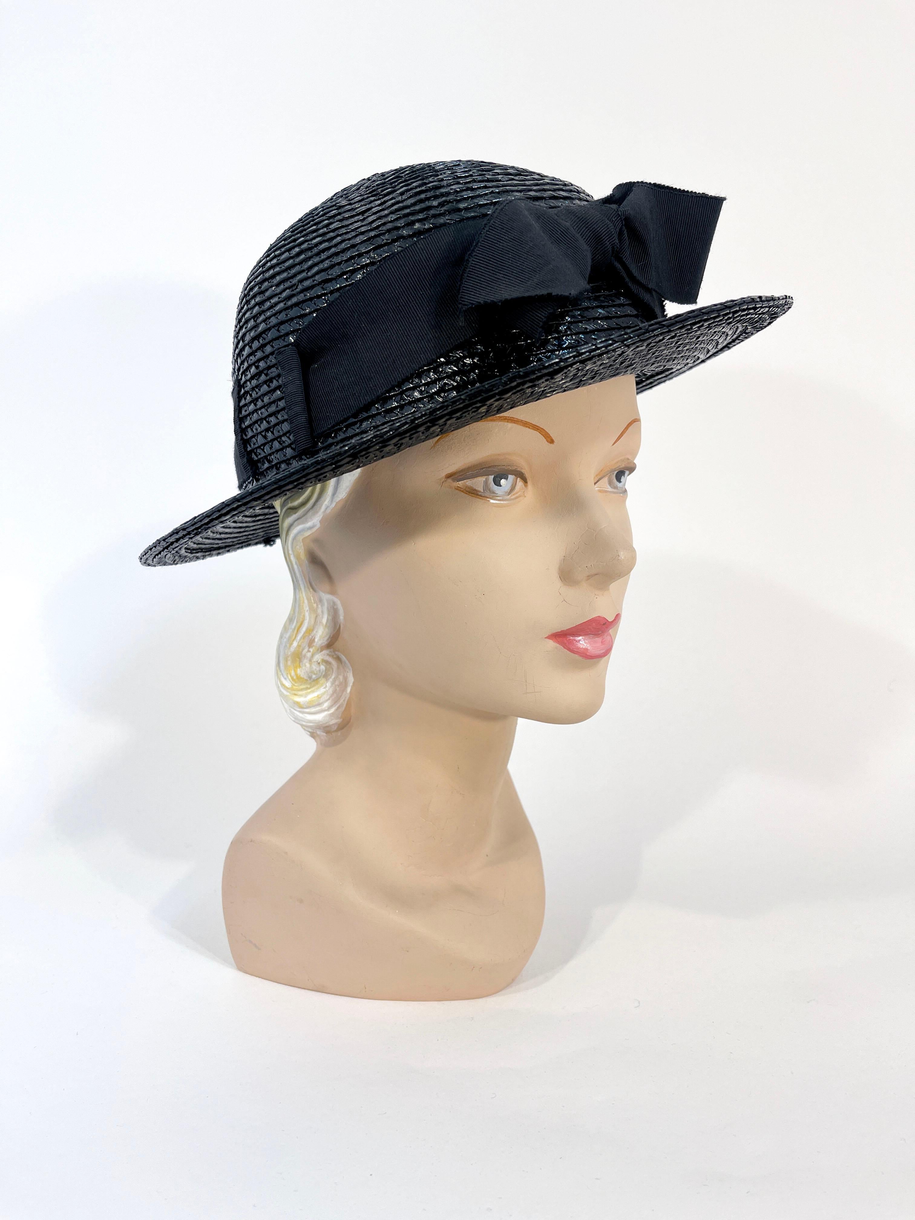 1890s Chanel black raffia boater hat featuring a wide 1.5 inch grow grain hand band, a centered enlarged tied bow, a domed crown, and a flat brim (approx. 2 in.). The gros grain band is woven through a few hat cutouts making the band secure. The