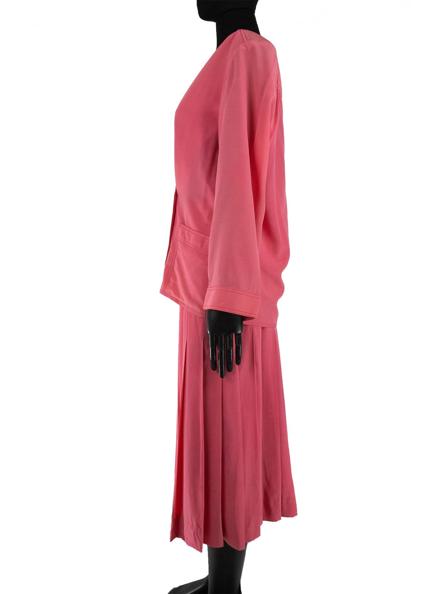 A Chanel two-piece silk crêpe suit from the 1980s, consisting of a loose-fitting, lightweight shirt and skirt. The shirt has a deep v neckline and is crossed over and fastened with double-breasted buttons. It has shoulder pads for a structured