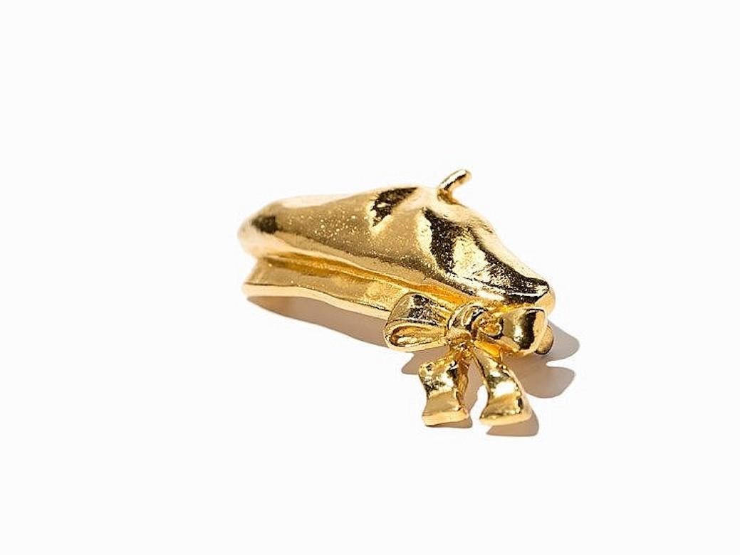 This gold-plated metal brooch, circa 1980, by Chanel features a beret with a bow and embodies the feminine French elegance of Coco Chanel. The term 'beret' became modish when Napoleon III became fascinated by this curious hat on his common visits to