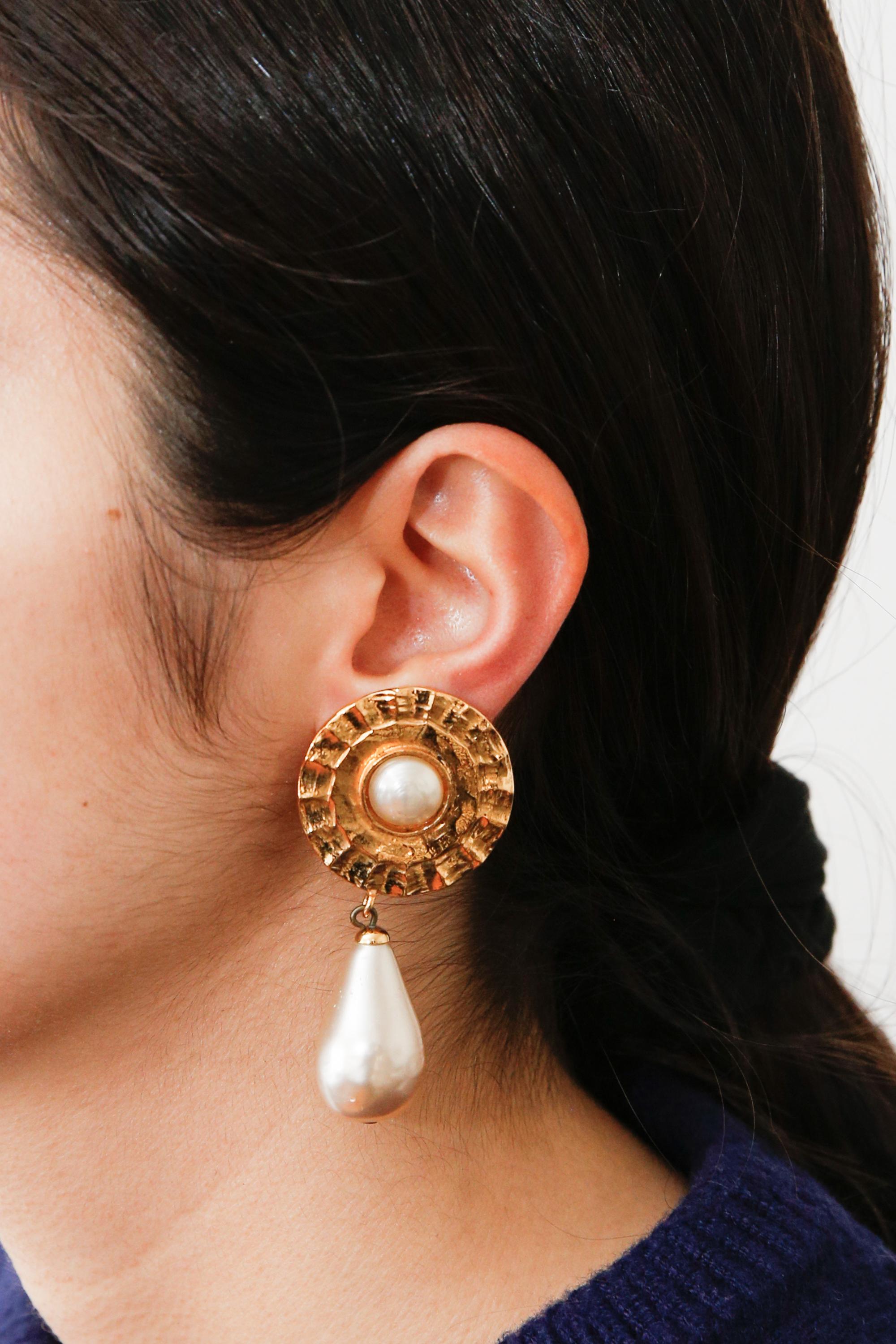 Chanel Gold-tone & faux-pearls long pendant clip-on earrings featuring a round gold-tone shape, a central and a pendant faux-pearl beads, a long faux-pearl drop, a clip-on fastening, and a back plaque pitted. 
They come as a pair. Delivered in