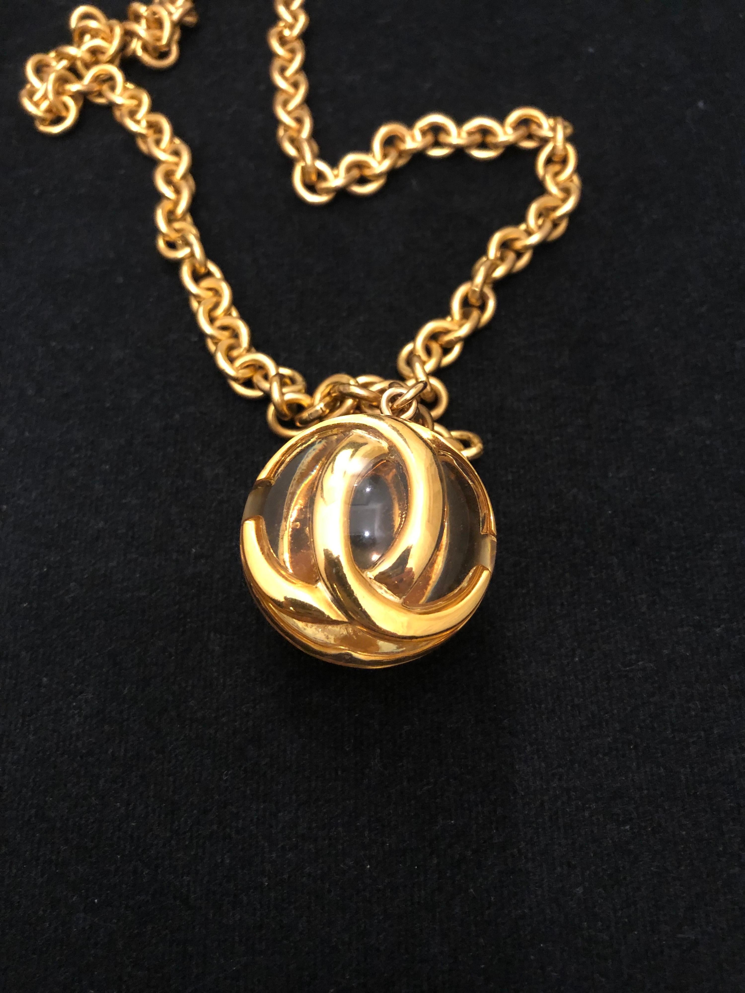 1980s Chanel gold toned long chain necklace featuring 3-dimensional CC charm in a transparent resin ball. Stamp 2 5 made in France. Length measures 86cm Charm 3.4cm. Spring ring fastening.

Condition: Some signs of wear on chain and resin ball