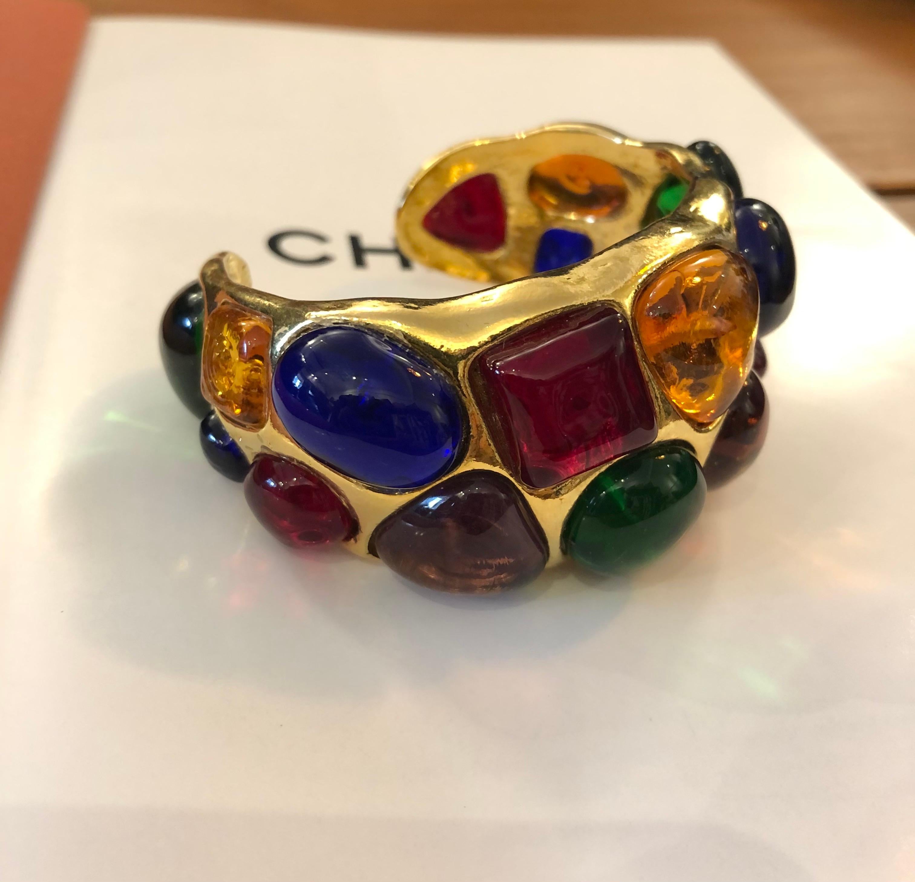 1980s Chanel gold toned cuff bangle adorned with 17 multicolored Gripoix. Stamped 26 made in France. Circumference measures approximately 16 cm Width 3.3 cm Opening 1.6 cm. Comes with dust bag and box.

Condition: Minor signs of wear. Generally in