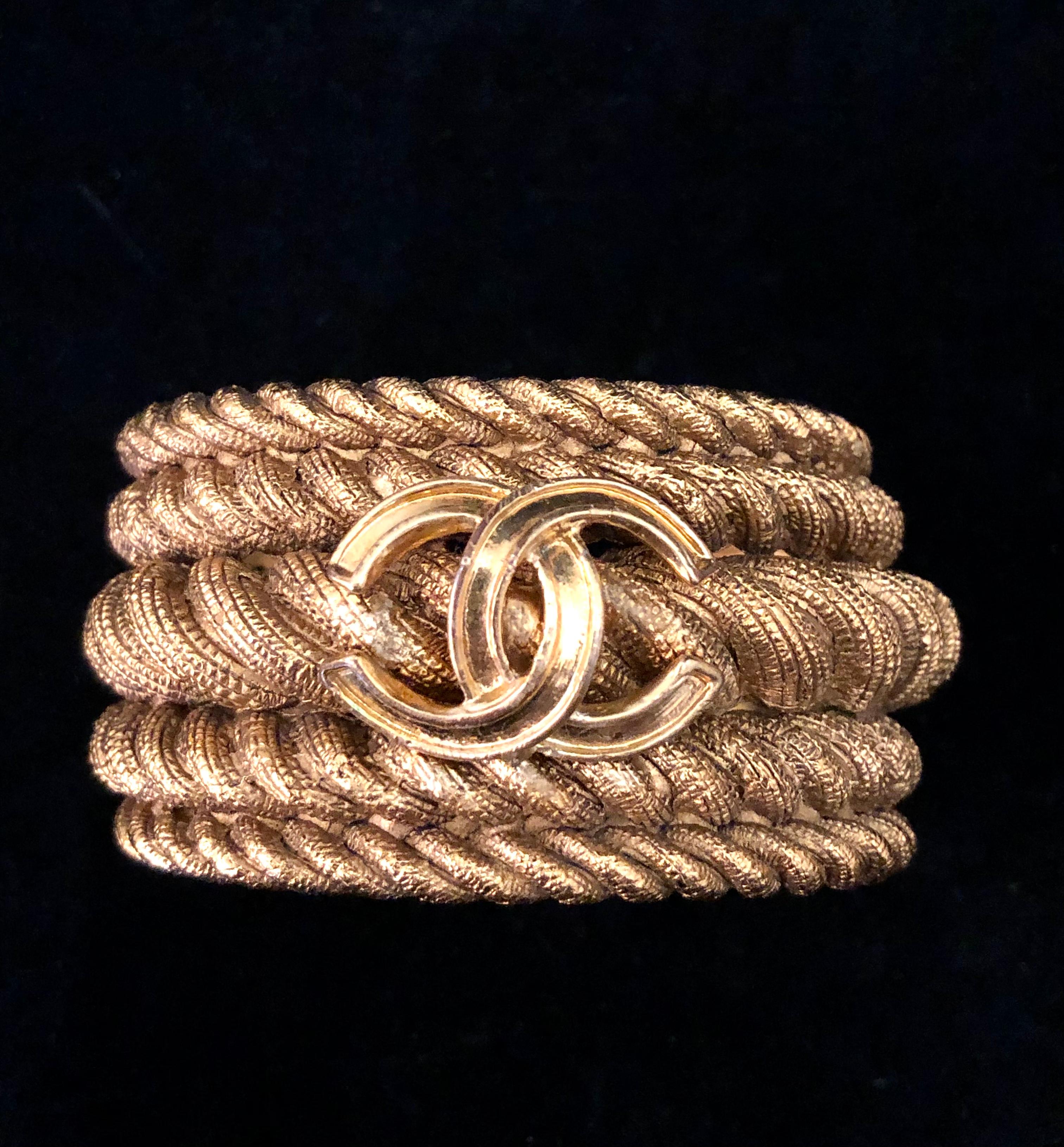 1980s Chanel cuff bracelet in gold toned ropes combined together adorned with a gold toned CC logo. Circumference measures approximately 16.5 cm Width 3.5 cm. Stamped 25 made in France.

Condition: Exterior shows minor signs of wear. Interior