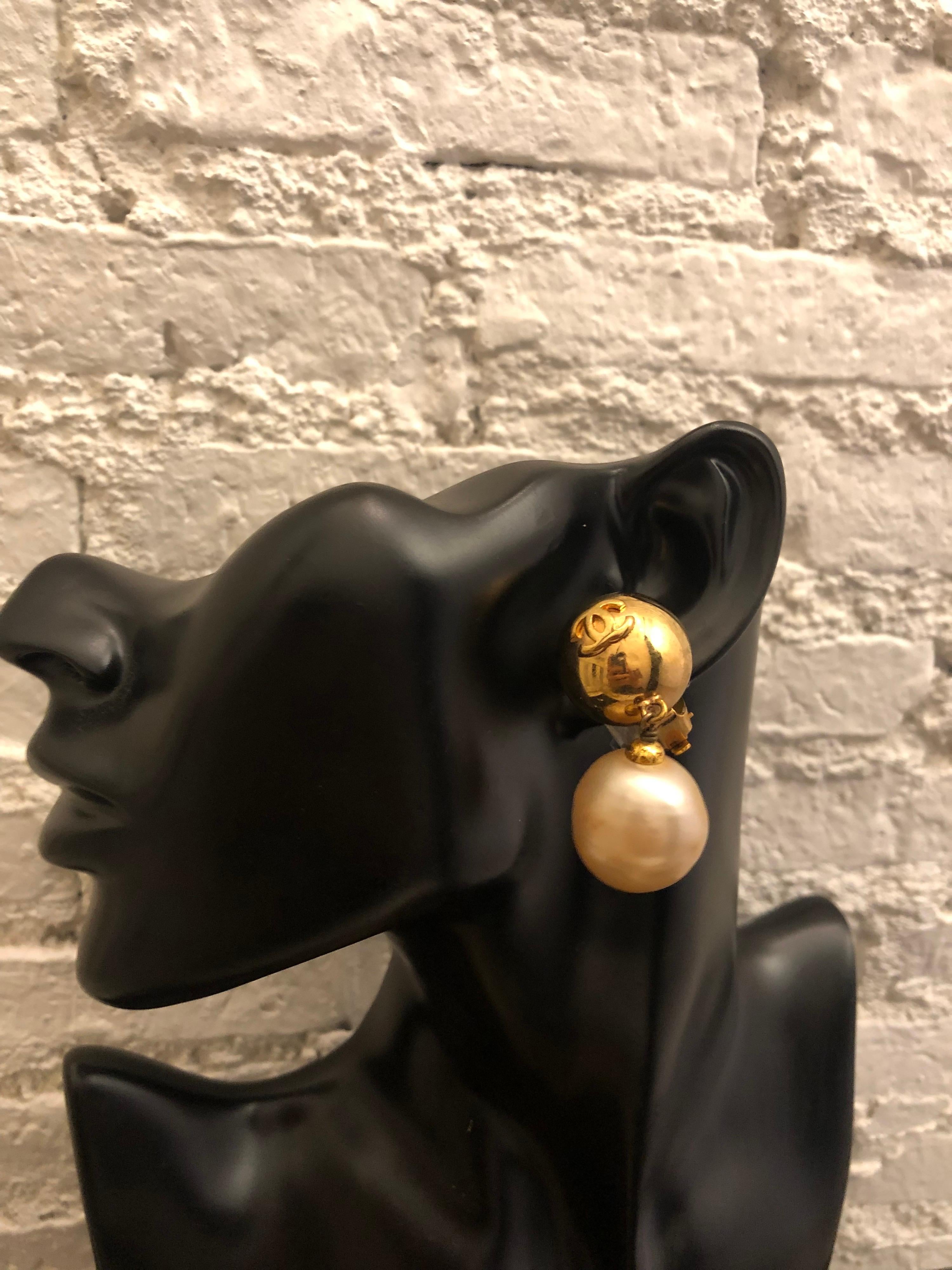 1980s vintage Chanel gold toned earclips featuring gold toned sphere with dangle faux pearl. Stamped Chanel 27 made in France. Measures approximately 5 x 2.5 cm. Comes with box. 

Condition: Minor signs of wear with minor scratches and tarnish