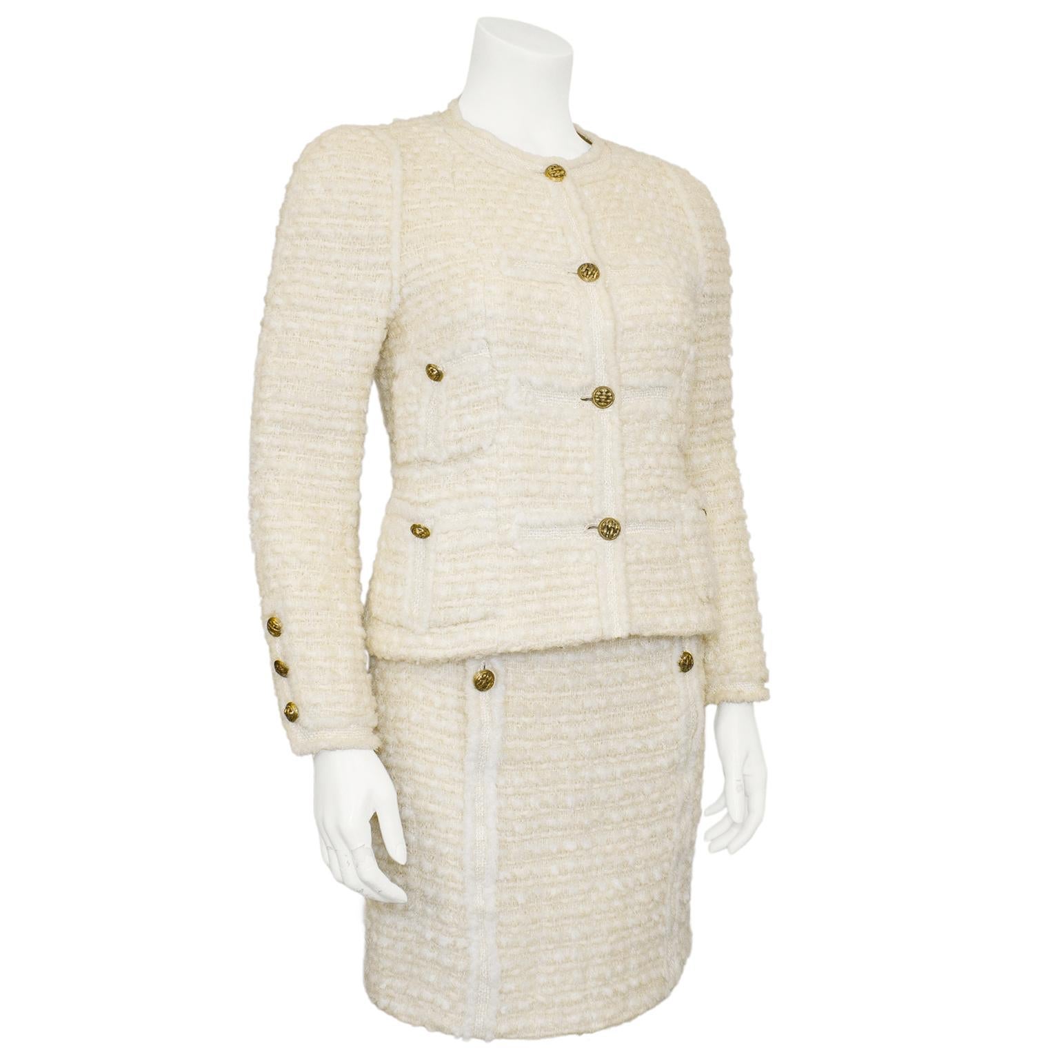 Absolutely stunning and classic 1980's Chanel Haute Couture cream wool boucle skirt suit. Collarless jacket with four patch pockets. Gold tone metal round woven motif buttons. The boucle is contrasted with tweed details along centre of jacket and on