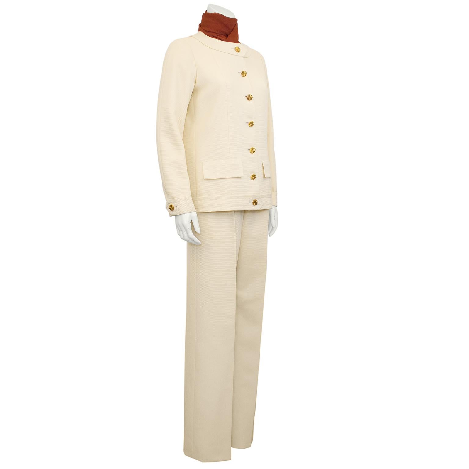 Incredible Chanel Haute Couture cream wool pantsuit from the early 1980s. Collarless jacket with faux flap pockets. Lovely round gold tone metal buttons with a twisted edge detail. Cream silk lining with the iconic Chanel interior hem chain. High