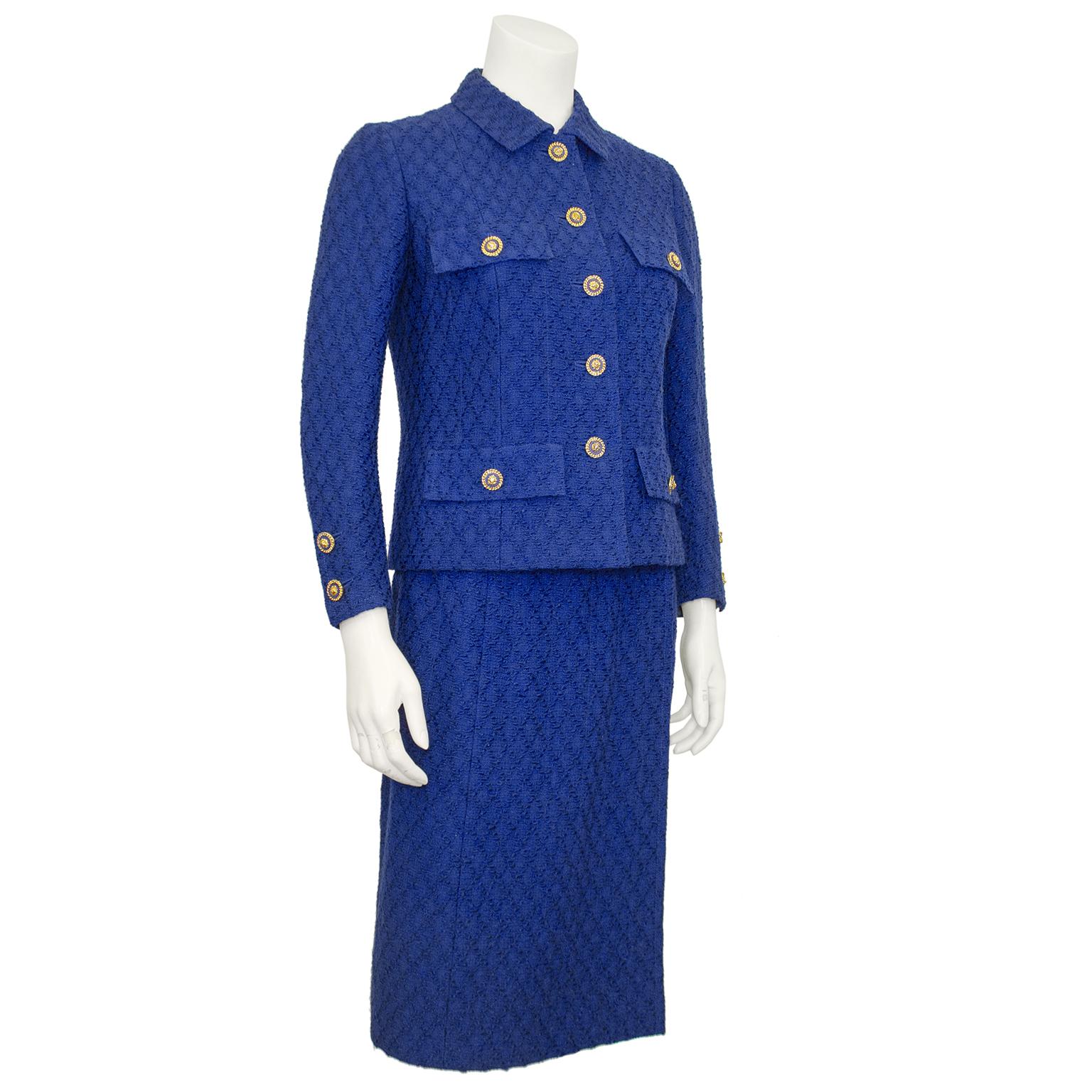 Tailleur jupe Chanel Haute Couture classique des années 1980, en laine bouclée bleu roi à motifs de losanges. La veste est entièrement doublée et s'achève à l'ourlet par la chaîne dorée emblématique. Cinq boutons à tête de lion en métal bleu roi et