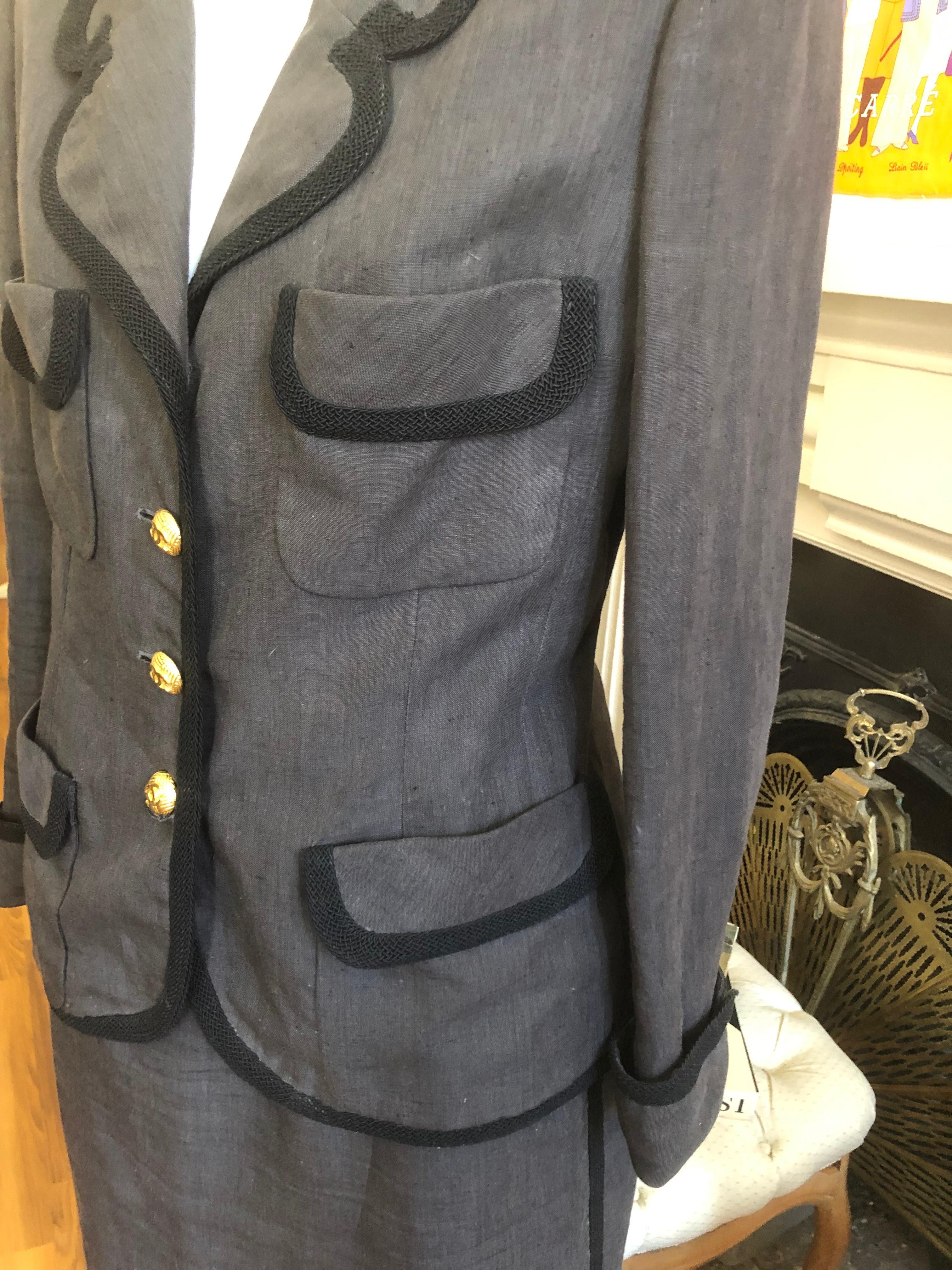 This is a late 1980s linen suit, with black braiding accents, on both the jacket and the skirt. The suit was designed by Karl Lagerfeld and is part of Collection 22. It has a notched lapel; cc silk lining; four pockets, and beautiful goldtone