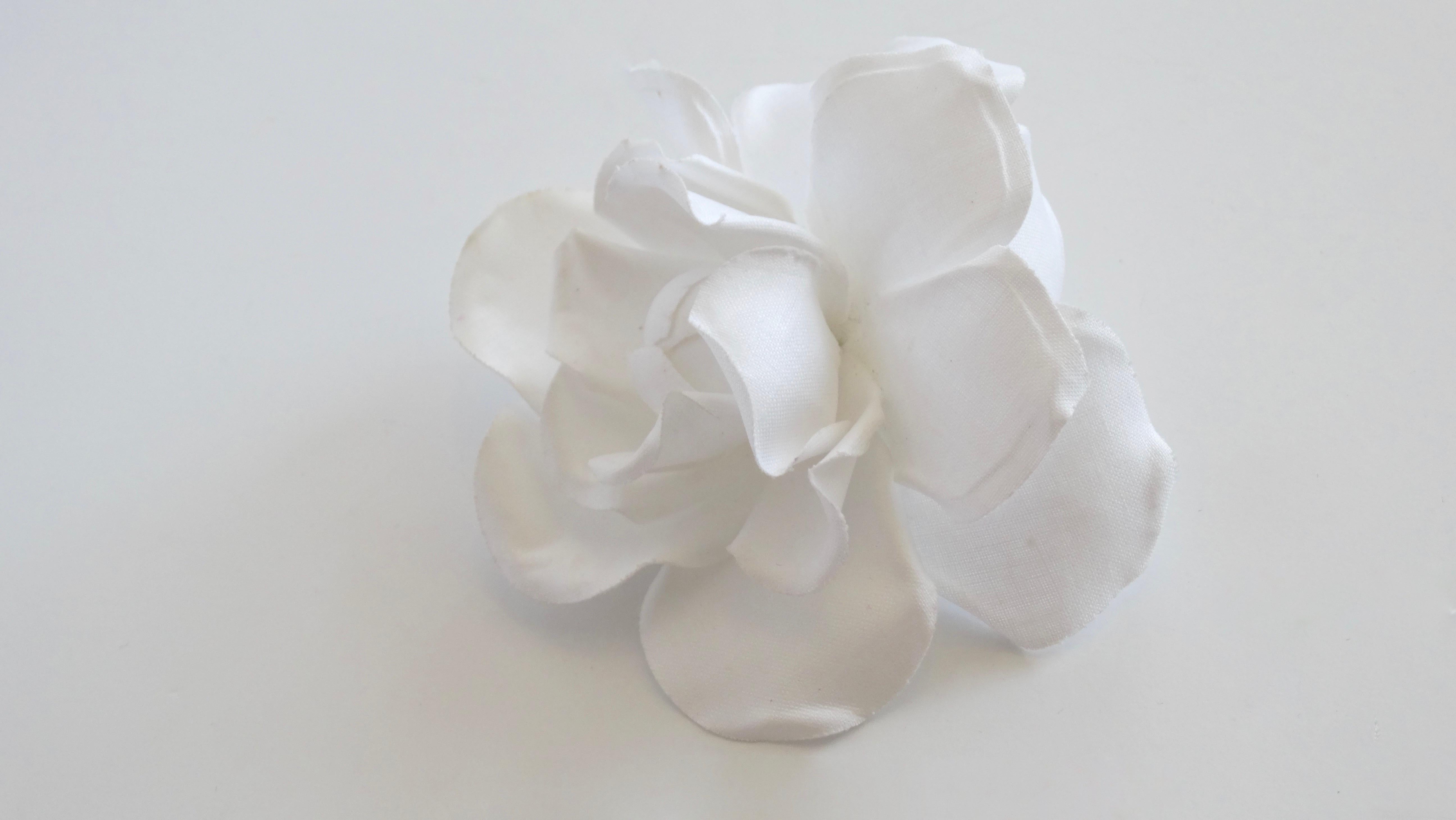 Be the ultimate Chanel girl with this brooch! Circa early 1980s, this brooch is made of white cotton fabric and crafted into the signature Chanel Camellia flower. Classic and timeless, this brooch is the perfect addition to your favorite Chanel