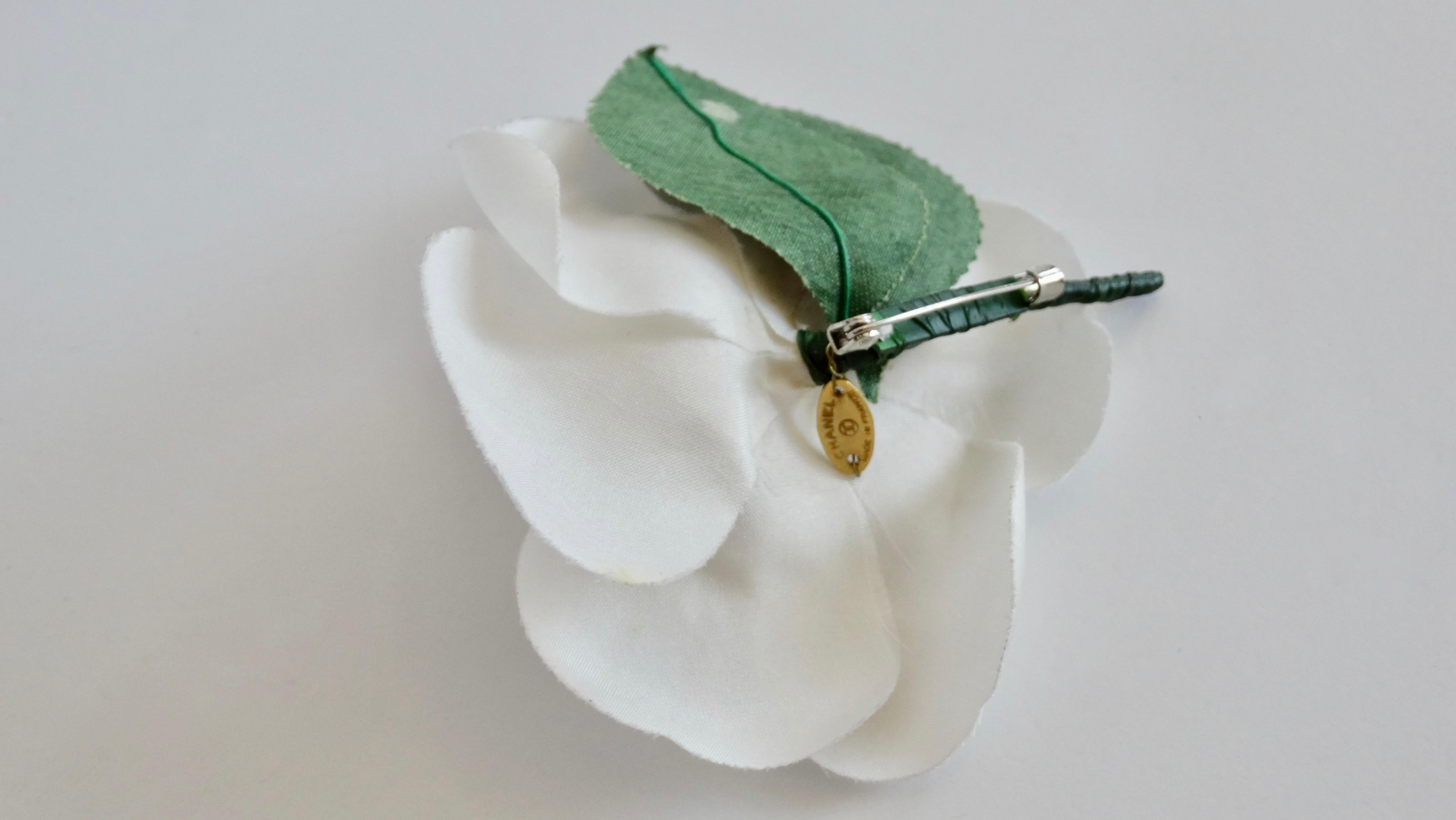 Be the ultimate Chanel girl with this brooch! Circa early 1980s, this brooch is made of white fabric and crafted into a gorgeous white poppy flower with a yellow center and two leafs. Classic and timeless, this brooch is the perfect addition to your