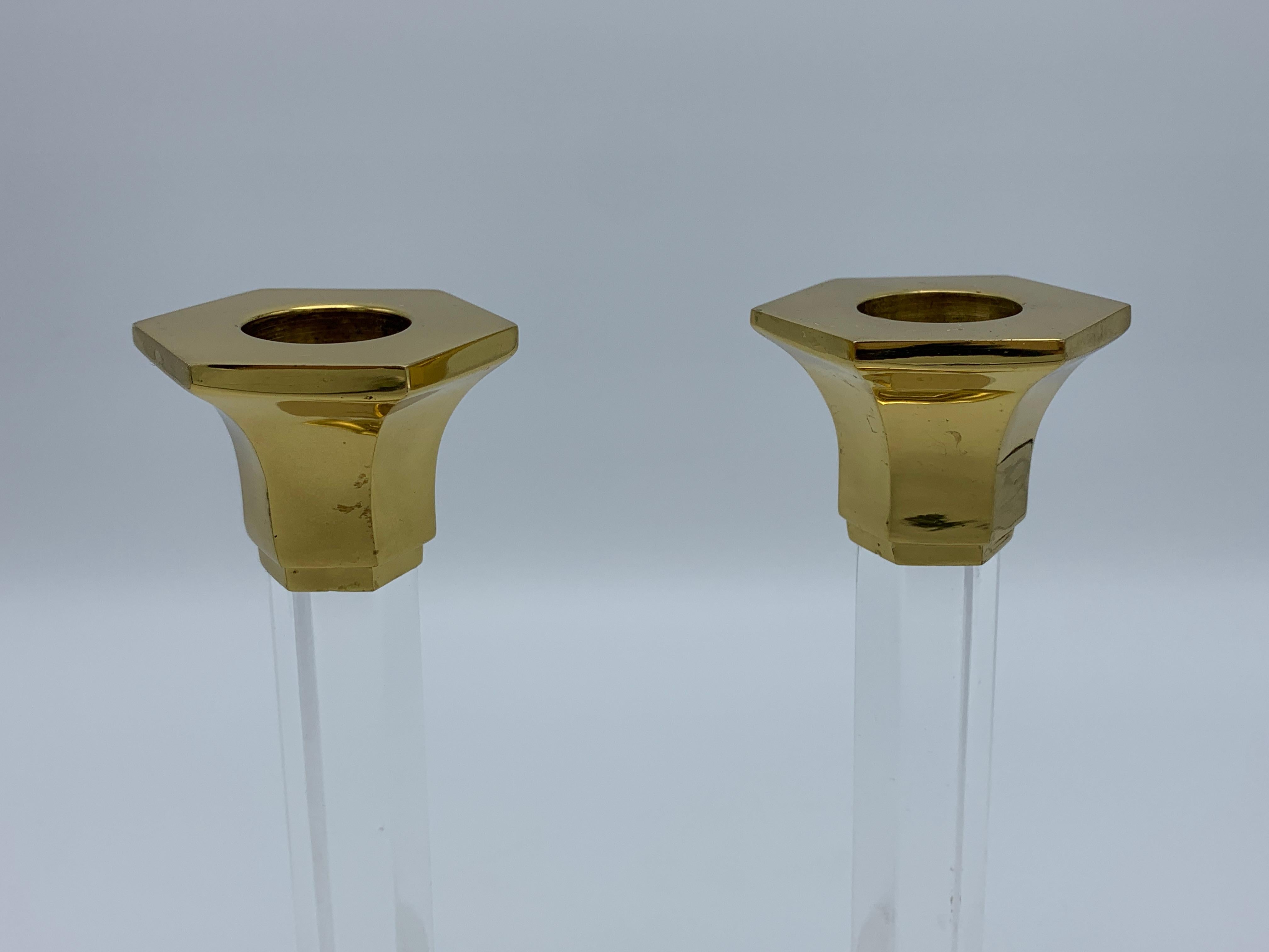 Listed is a stunning, pair of 1980s Charles Hollis Jones style candlestick holders. The pair have thick, lucite hexagon pillars with heavy polished brass bases and collars. Heavy, weighing nearly 2lbs/pair.